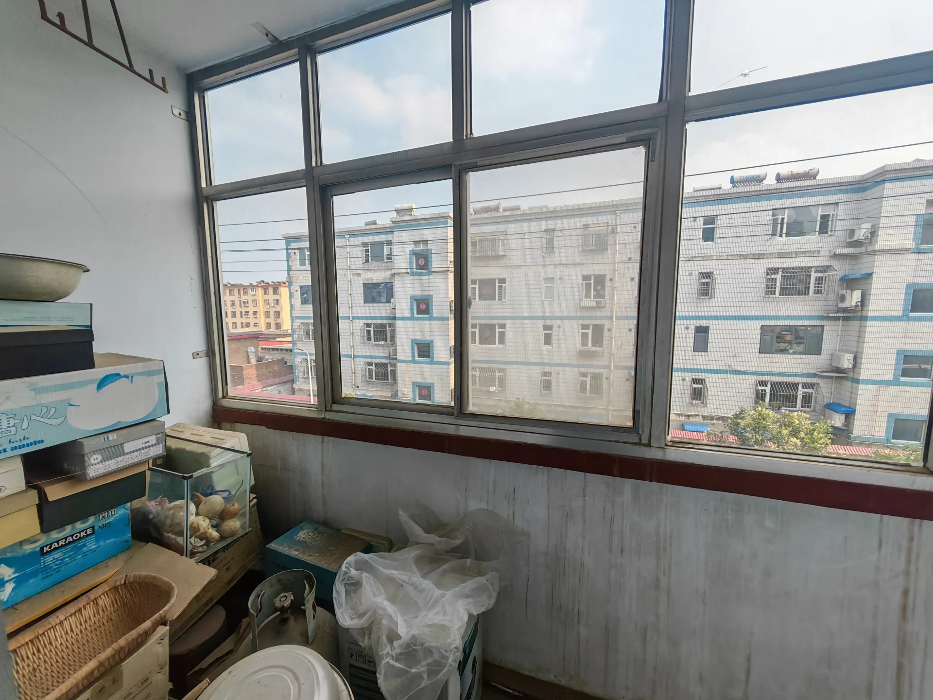 小公寓，阳台可俯瞰城市，有窗户和城市景色，阳台配有椅子和小桌，还有几个箱子和一个碗，空间温馨。