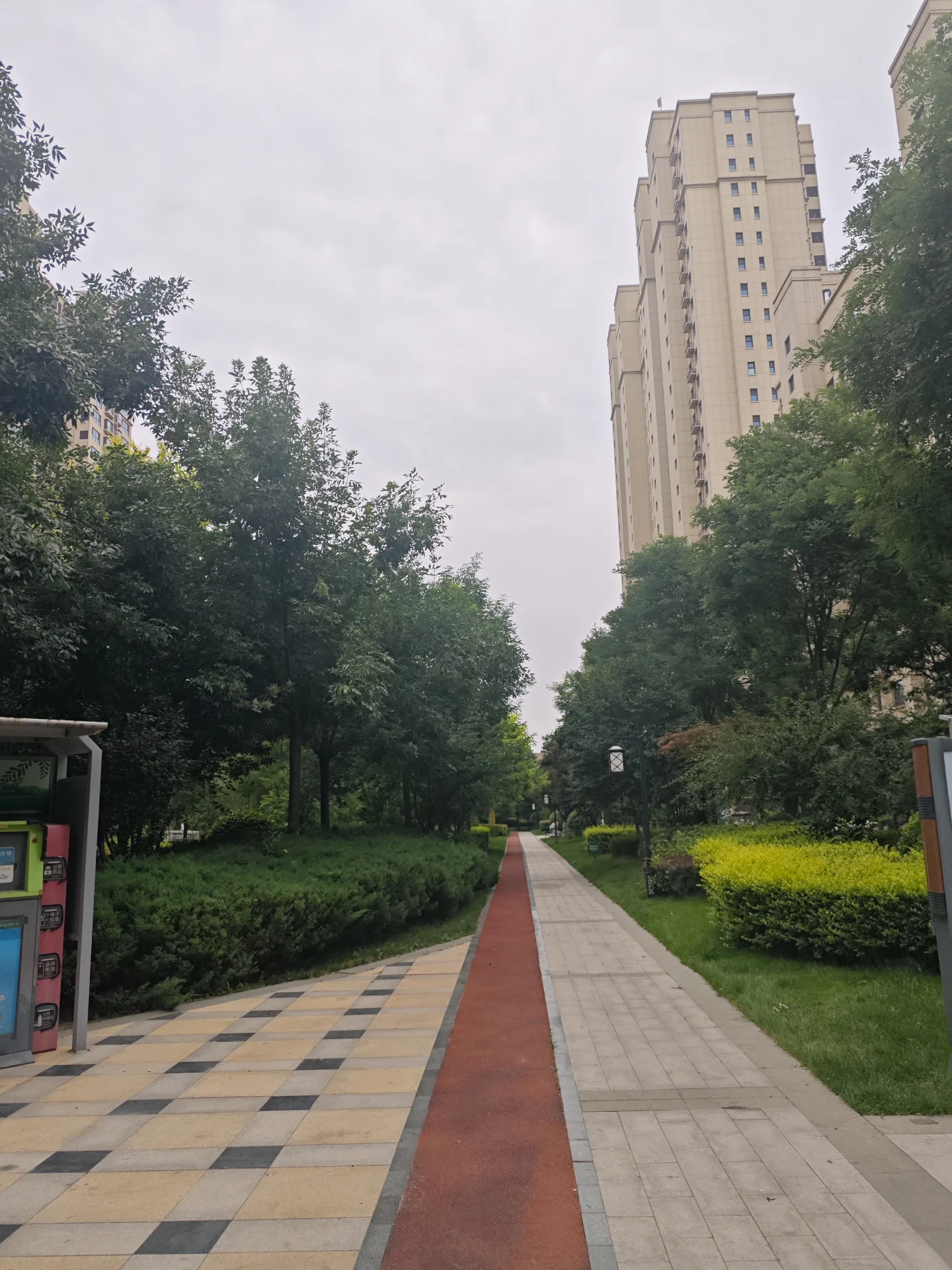 高层白色住宅楼的外部立面清晰可见，周围环绕着茂密的绿化带和树木，整体呈现出宁静、和谐的社区环境氛围。