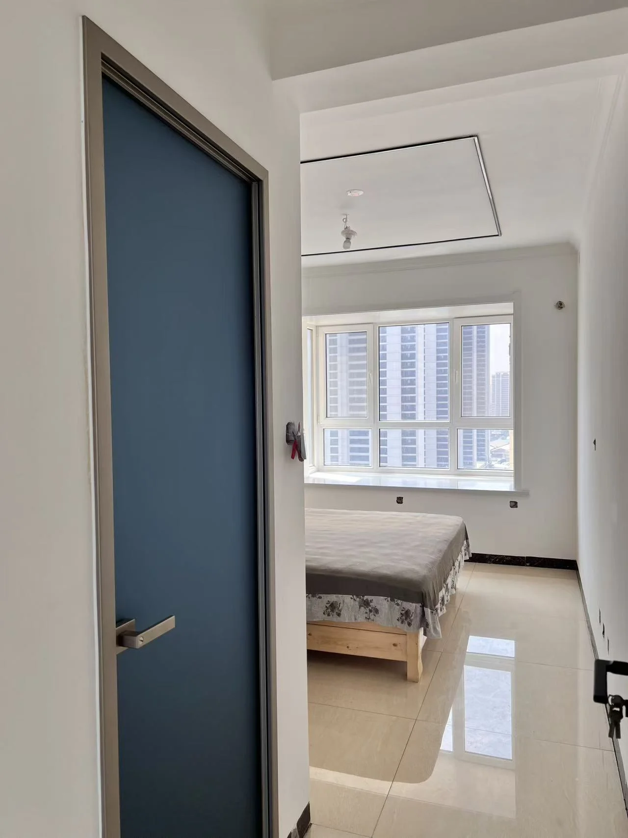 卧室和卫生间空间，墙面采用浅色调，地面铺设米色瓷砖，采光良好，整体呈现现代简约装修风格，空间整洁舒适。