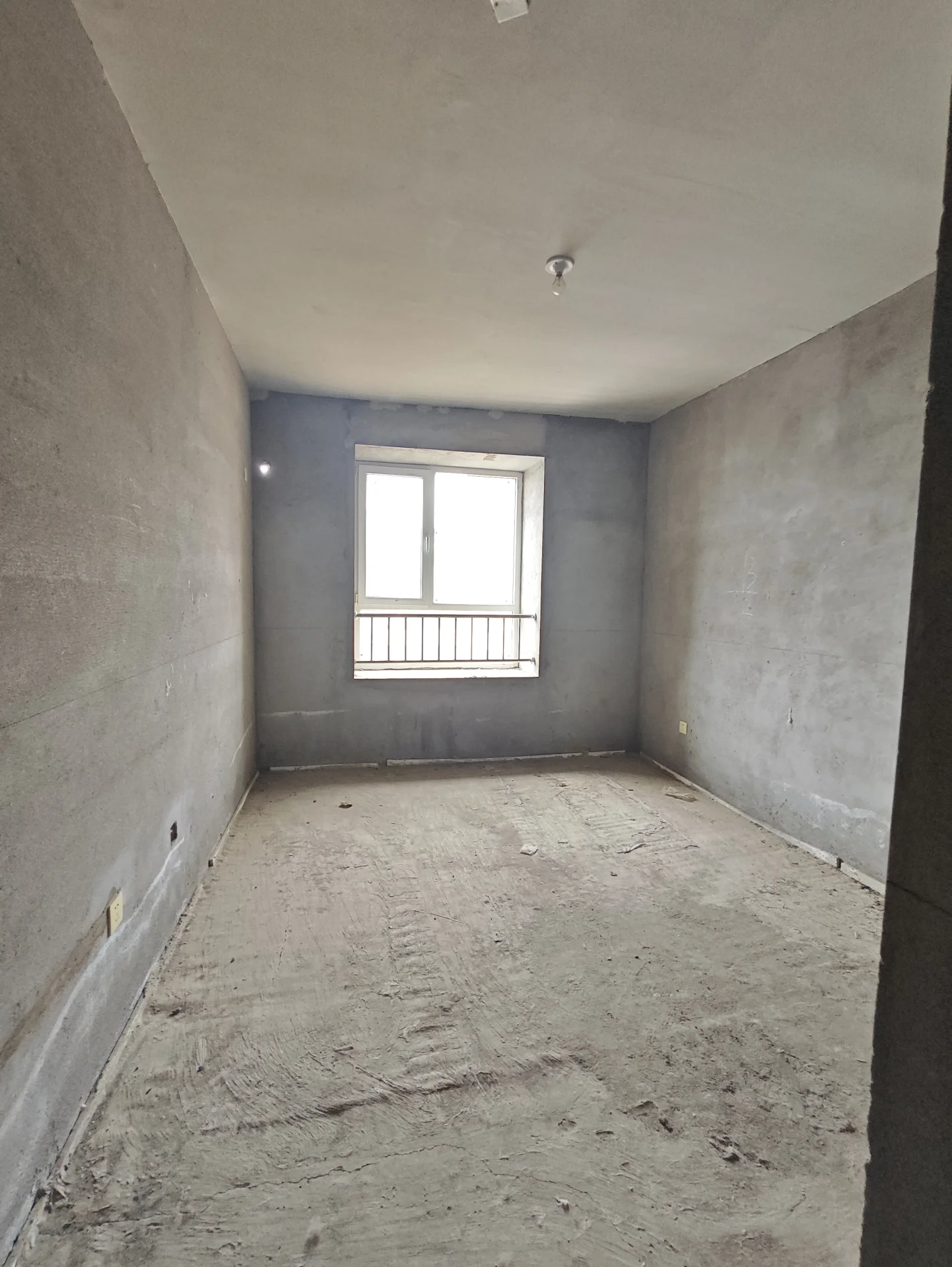 空旷房间，墙面和地面均为水泥材质，无家具和装饰，简约空旷。墙面未完成，房间内无个人触感或家具。