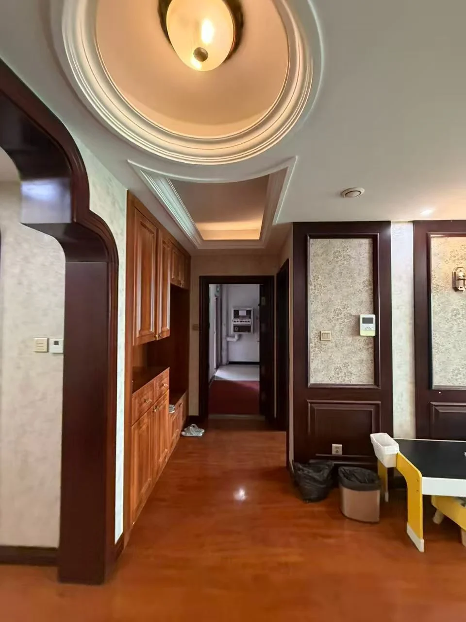 空旷房间，木质地板和墙壁，散落几件家具，如椅子和餐桌，氛围略显阴沉，可能为地下室或老旧建筑的一部分。木质地板和墙壁营造出一种质朴的感觉。