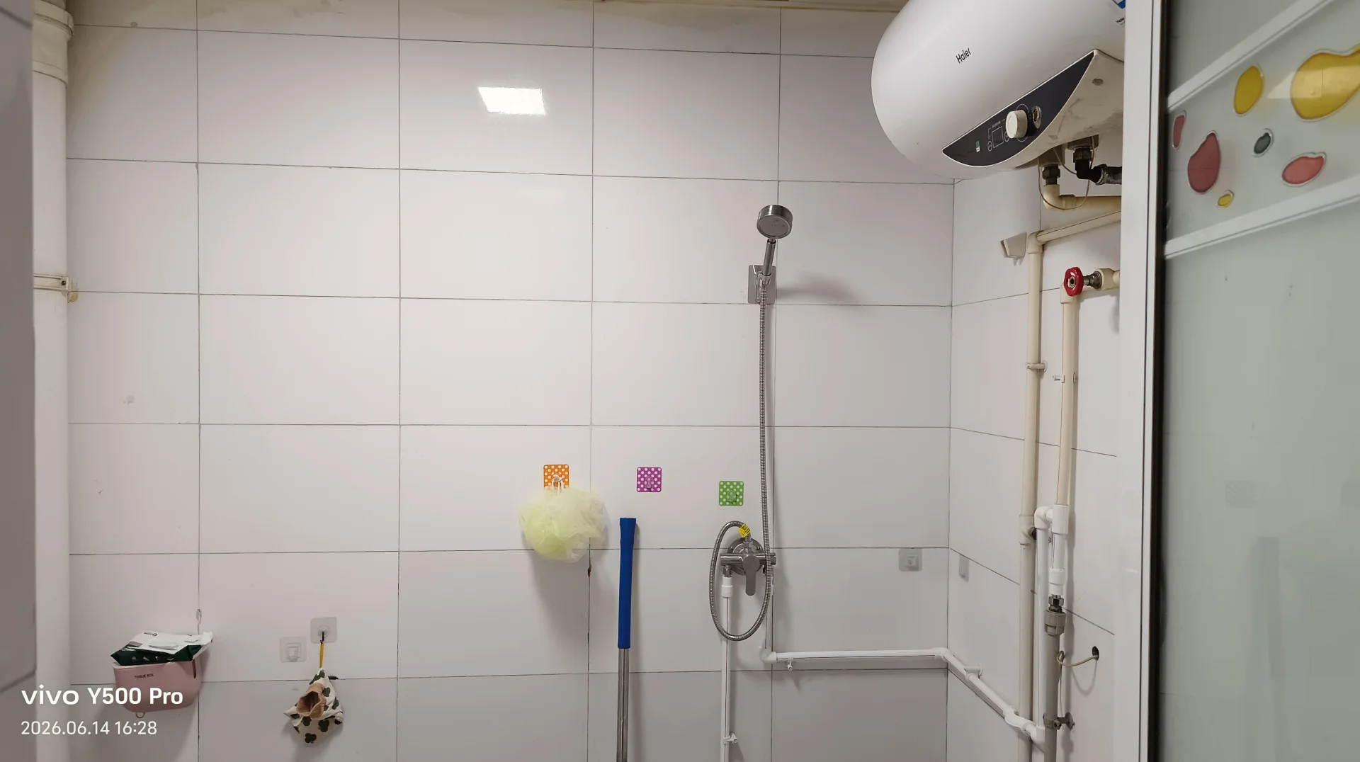 卫生间，白色瓷砖墙面，白色淋浴间，墙上有一台白色热水器，屋内有一台白色马桶，干净整洁。