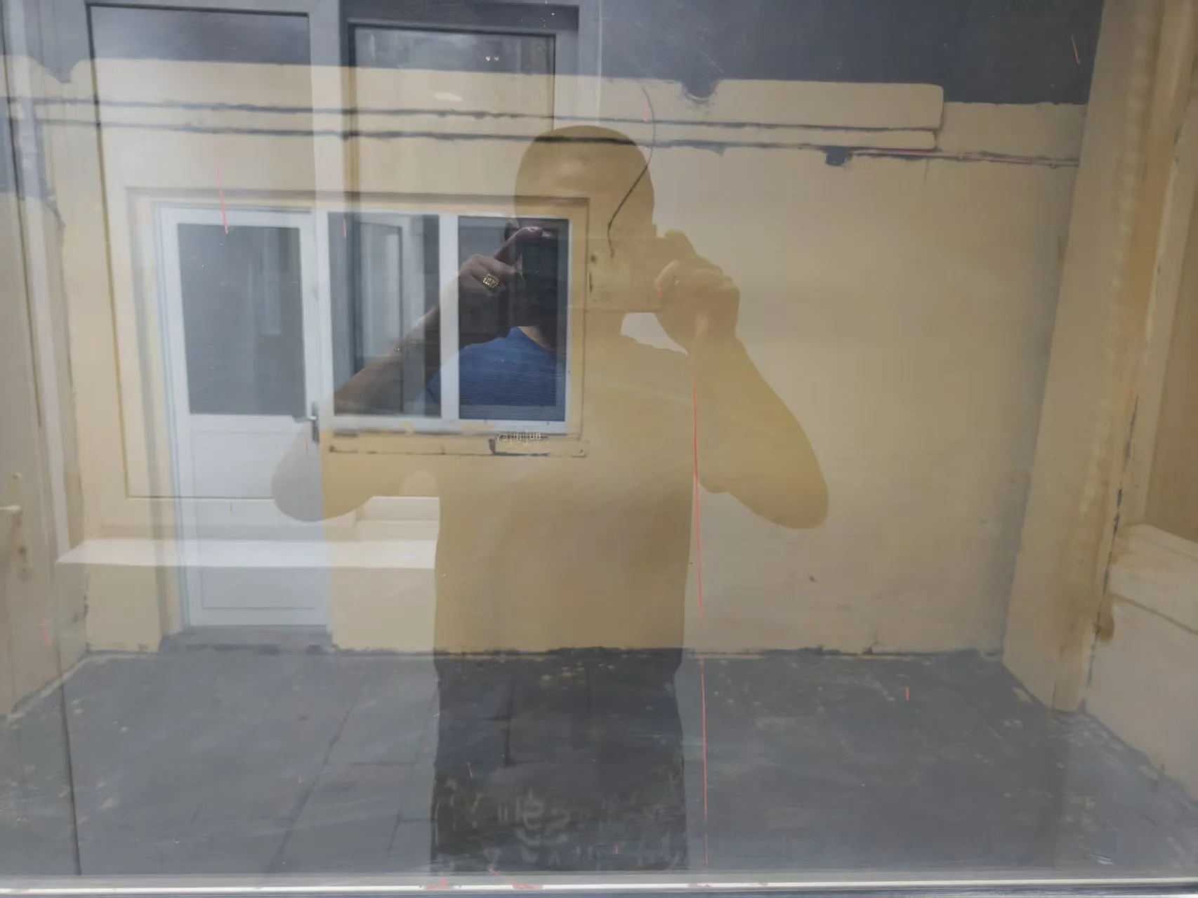 一张照片显示一个男人站在窗户前，手里拿着手机听电话。窗户位于一栋建筑物内，可能是房子或公寓。场景氛围看起来平静而安静，男人正在打电话。场景中的主要物体包括男人、窗户和手机。