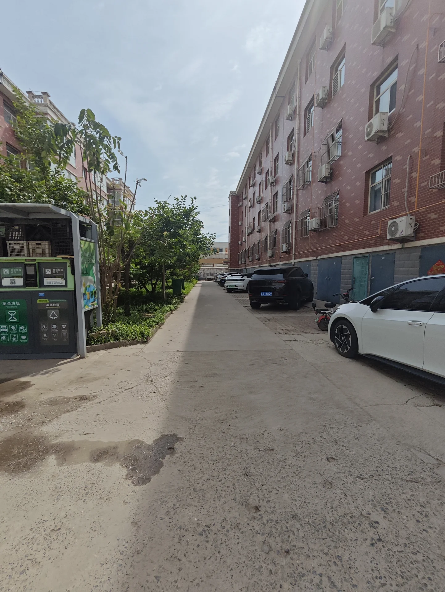 宁静的住宅街道，两侧停着几辆车，包括两辆白色车和一辆蓝色车。人行道上三人缓行，显得祥和宁静。红色砖墙的建筑增添了一种复古韵味。关键字:住宅街道 白色车 蓝色车 人行道 居民 宁静氛围 红色砖墙