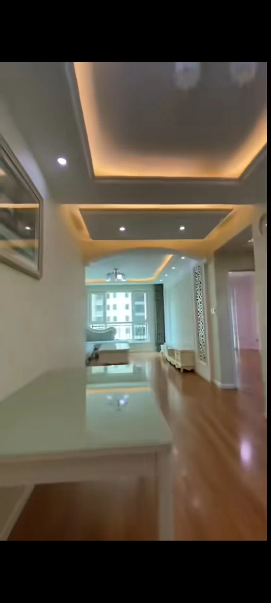 图片描绘了一个宽敞明亮的空间，配有白色桌子和椅子。房间里有一个大窗户，让自然光线充满整个空间。家具的摆放布置暗示着一个舒适和令人愉悦的氛围。房间里的物品包括沙发、餐桌和椅子。总的来说，场景传达出一种宁静和放松的感觉。