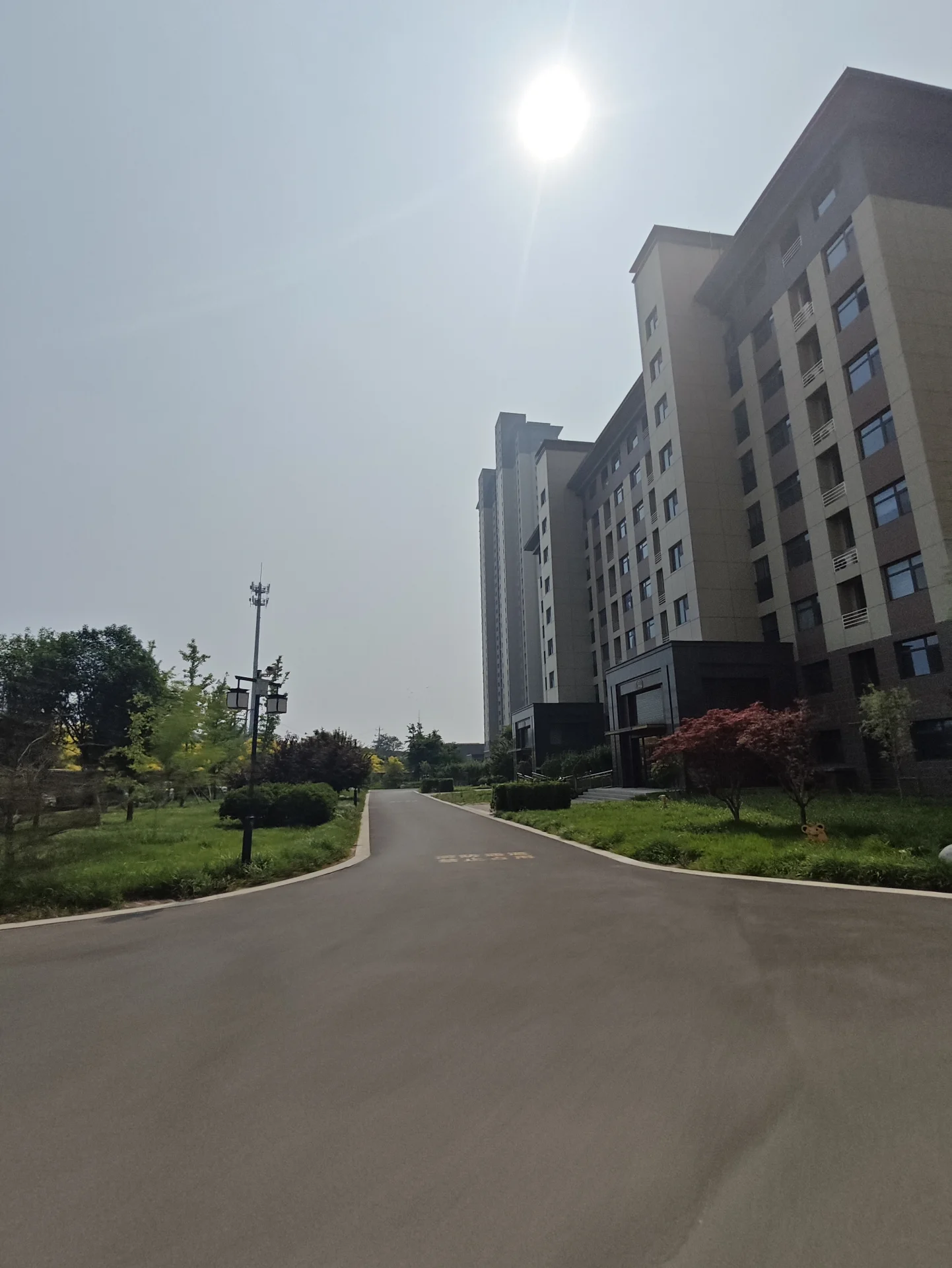 图片中的场景是一个大型停车场，位于一栋高楼上空。停车场空无一车一人，天空阳光明媚，周围被温暖的光线笼罩。背景中那栋高楼增添了城市的氛围，与开放的停车场形成了对比。关键字:停车场、高楼、城市