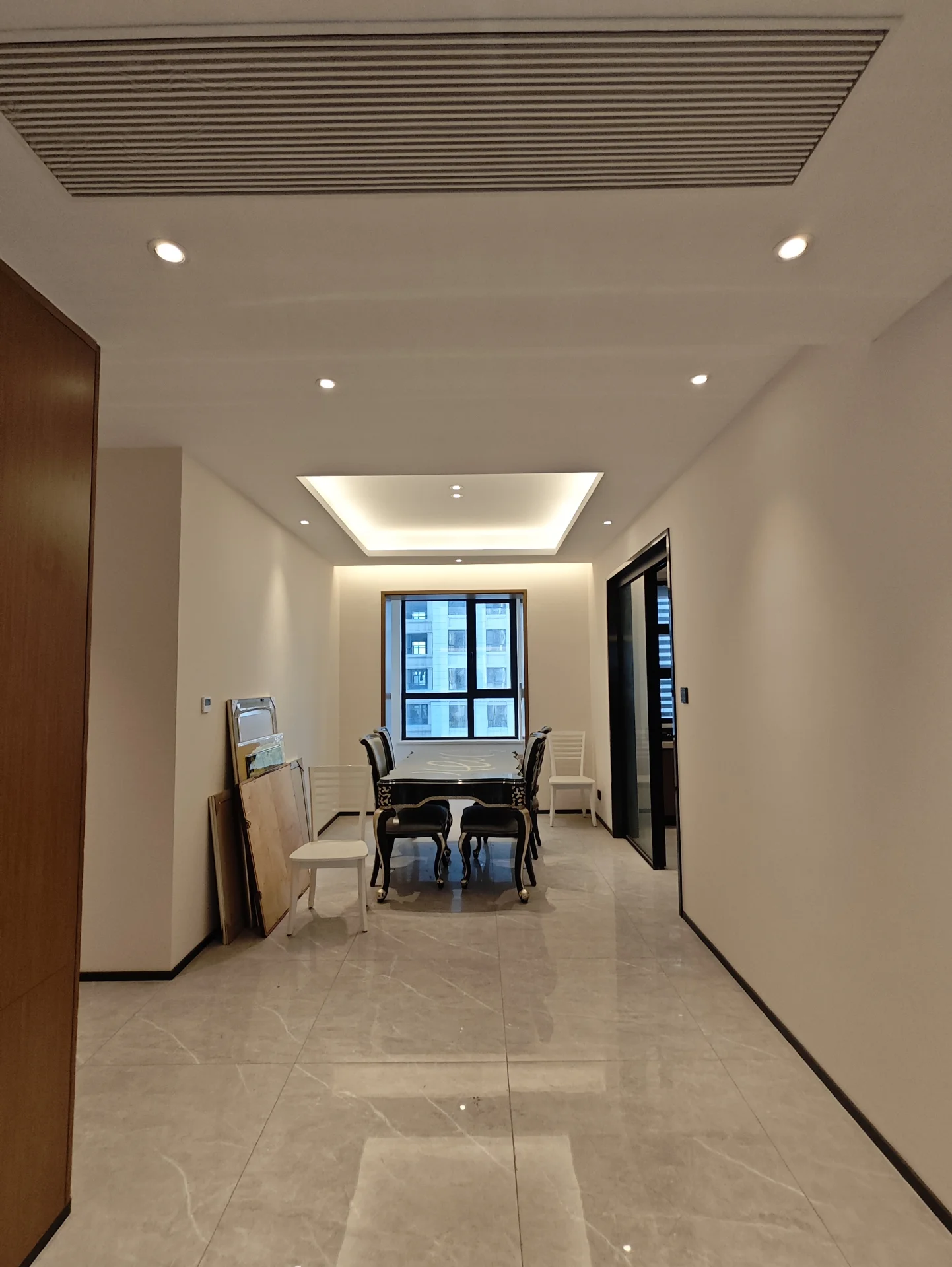 宽敞明亮的房间，白色墙壁和瓷砖地板，中央摆放着餐桌和椅子，一侧有窗户引入自然光。两把沙发靠墙而置，增添 seating选择。整体氛围干净整洁。关键字:宽敞 明亮 白色墙壁 瓷砖地板 餐桌 椅子 窗户 自然光 沙发 干净整洁