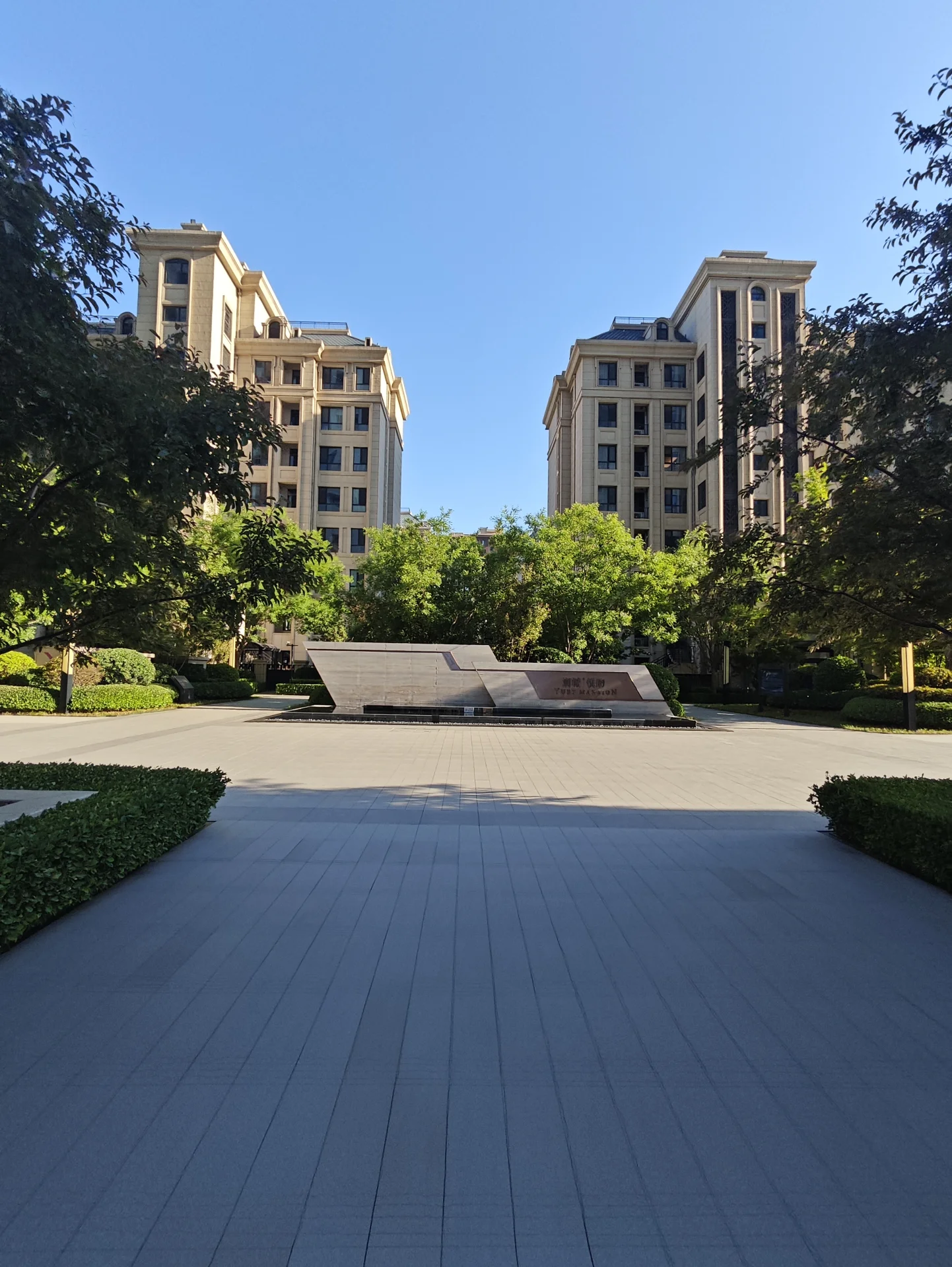 宽敞的庭院，现代高楼作为背景，营造出都市氛围。庭院整洁干净，阳光洒满，带来宁静感，是放松的好去处。关键字:宽敞庭院 现代高楼 都市氛围 整洁干净 阳光洒满 宁静感