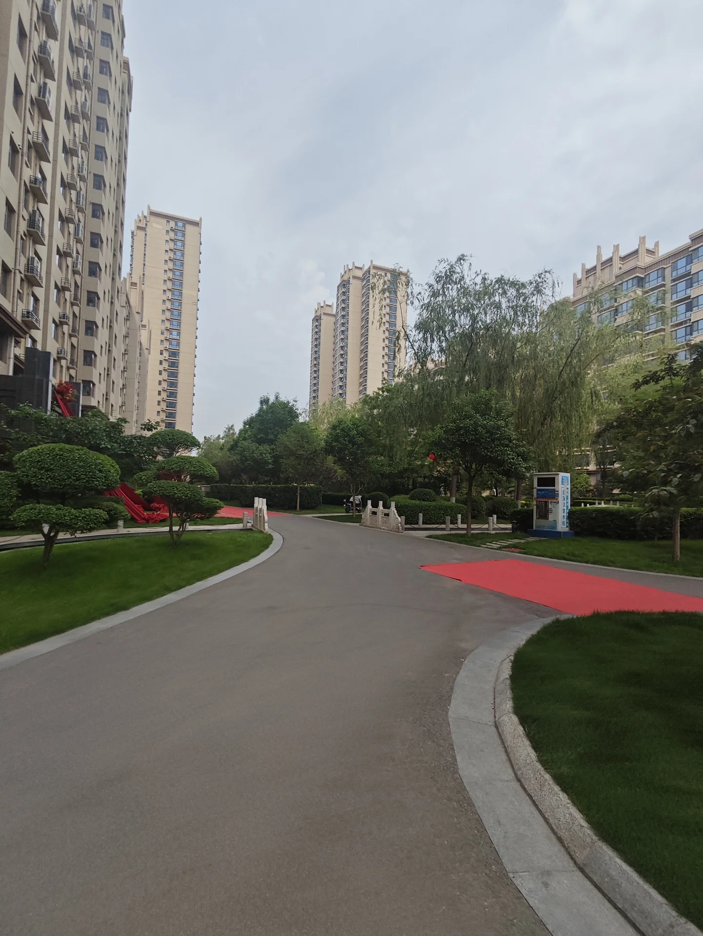 城市街道两侧是高耸的现代建筑，车辆有序停放，行人悠闲散步，宁静氛围中透出一丝绿意。关键字:城市街道 高耸建筑 现代风格 宁静氛围 绿化环境