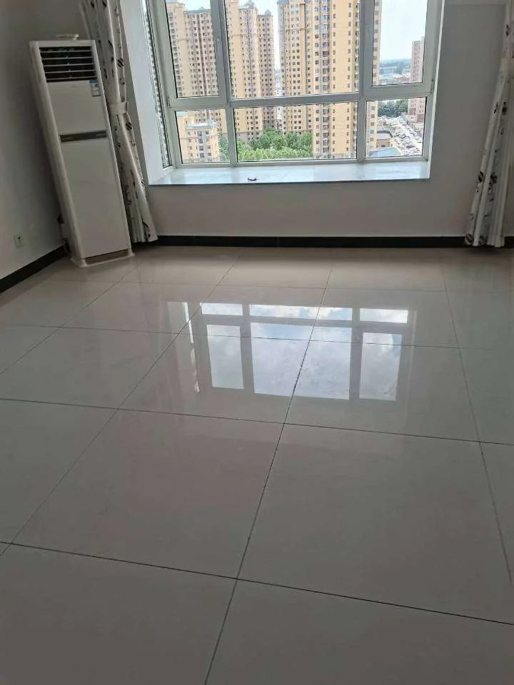 宽敞明亮的房间，洁白的地砖和墙面，窗外是城市天际线。角落里摆放着冰箱，整体氛围整洁宜人。关键字:大房间 白色瓷砖 城市天际线 冰箱 宽敞明亮 整洁宜人