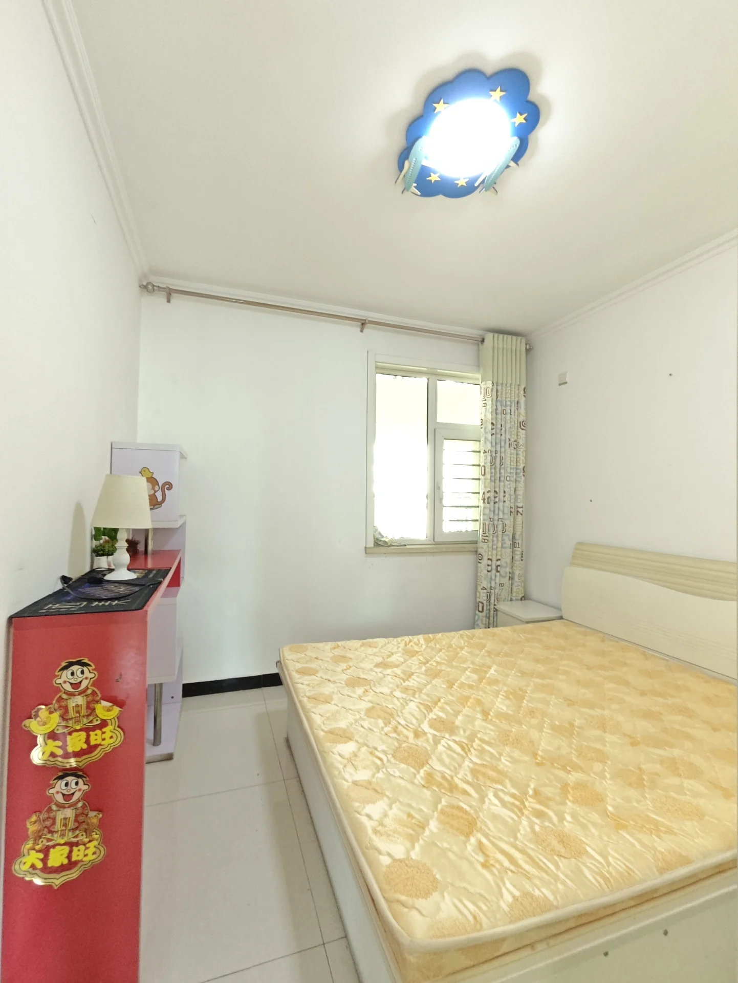 卧室以白色为主色调，大床铺有橙黄床品，上方吊灯营造温馨氛围。窗户引入自然光，旁边摆放的书籍暗示这里是阅读或放松的好去处。关键字:卧室 白色 大床 橙黄床品 吊灯 自然光 书籍