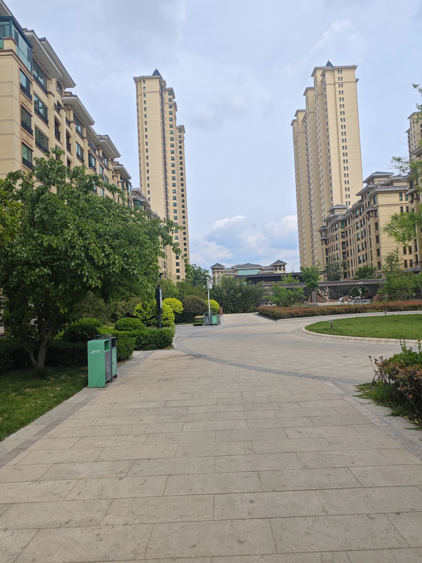 宁静的街道，两侧树木成荫，背景是高耸的现代建筑，营造出祥和的氛围。目前街道空无一人，仿佛能让人暂时逃离城市的喧嚣。关键字:宁静 树荫 现代建筑 祥和 空无一人 逃离喧嚣