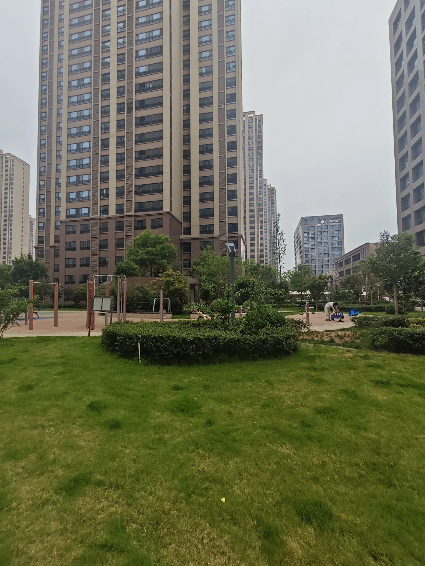 大型城市公园，周围有草地和树木，有几栋砖砌的高建筑物，氛围宁静。
