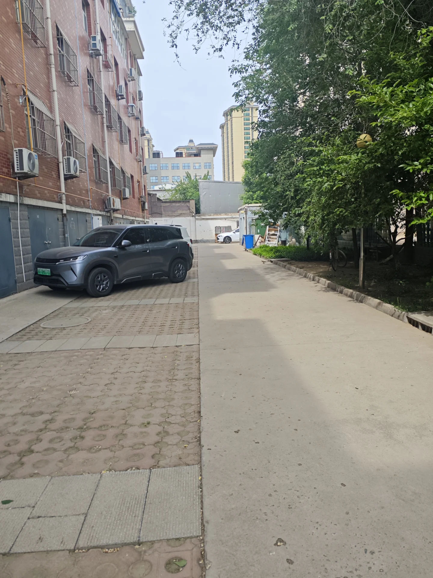 宁静的住宅街，几辆 parked汽车和树木点缀其间。黑色SUV停在路边，另一辆车稍远处，背景有辆卡车。街道上无行人或活动，营造出平静祥和的氛围。砖墙建筑配带阳台，充满复古韵味。路边树木增添宁静感，是居民宜居的好地方。关键字:宁静 住宅街 parked cars 树木 SUV 卡车 平静祥和 砖墙建筑 阳台 复古韵味
