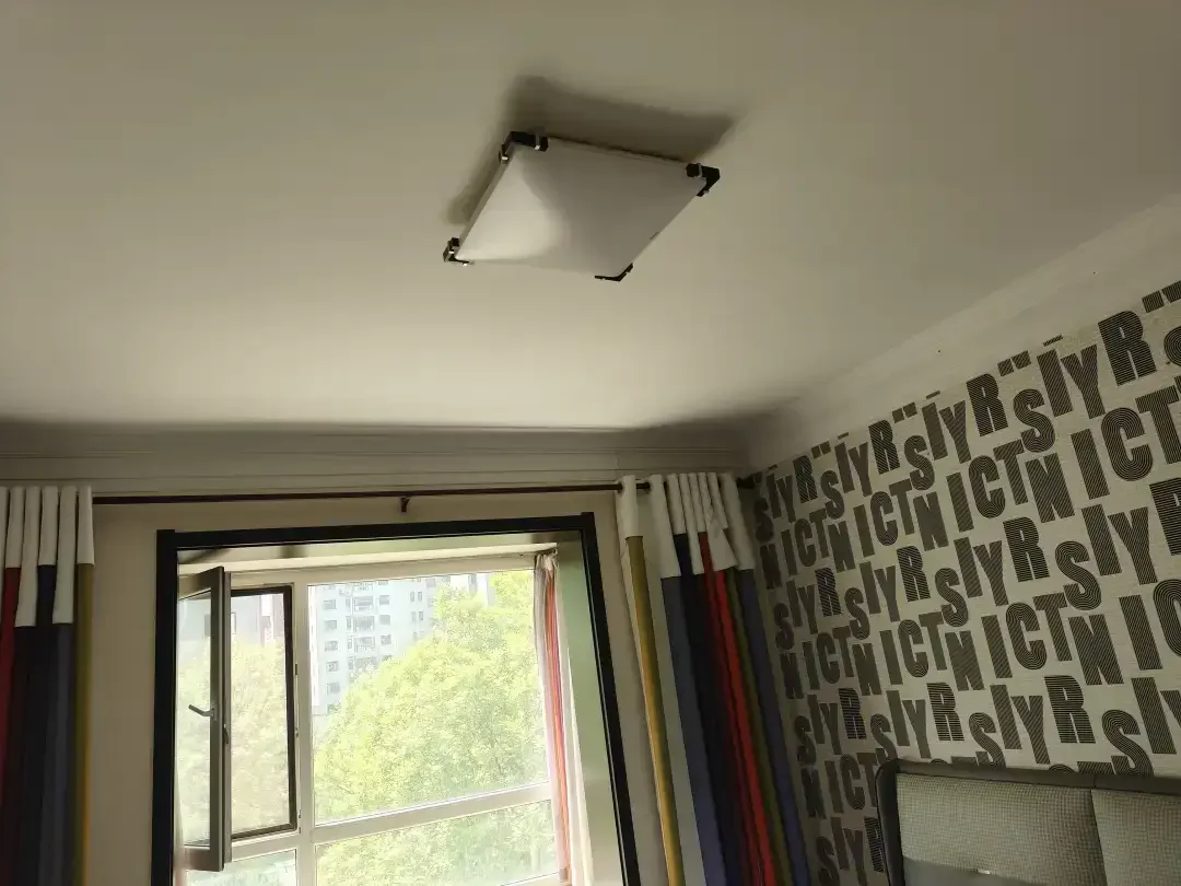 房间内有一扇窗户和一个灯具，窗户上方的灯座已被移除。房间显得昏暗，可能是由于灯具缺失或其他光源不足。关键字:房间 窗户 灯具 灯座 昏暗