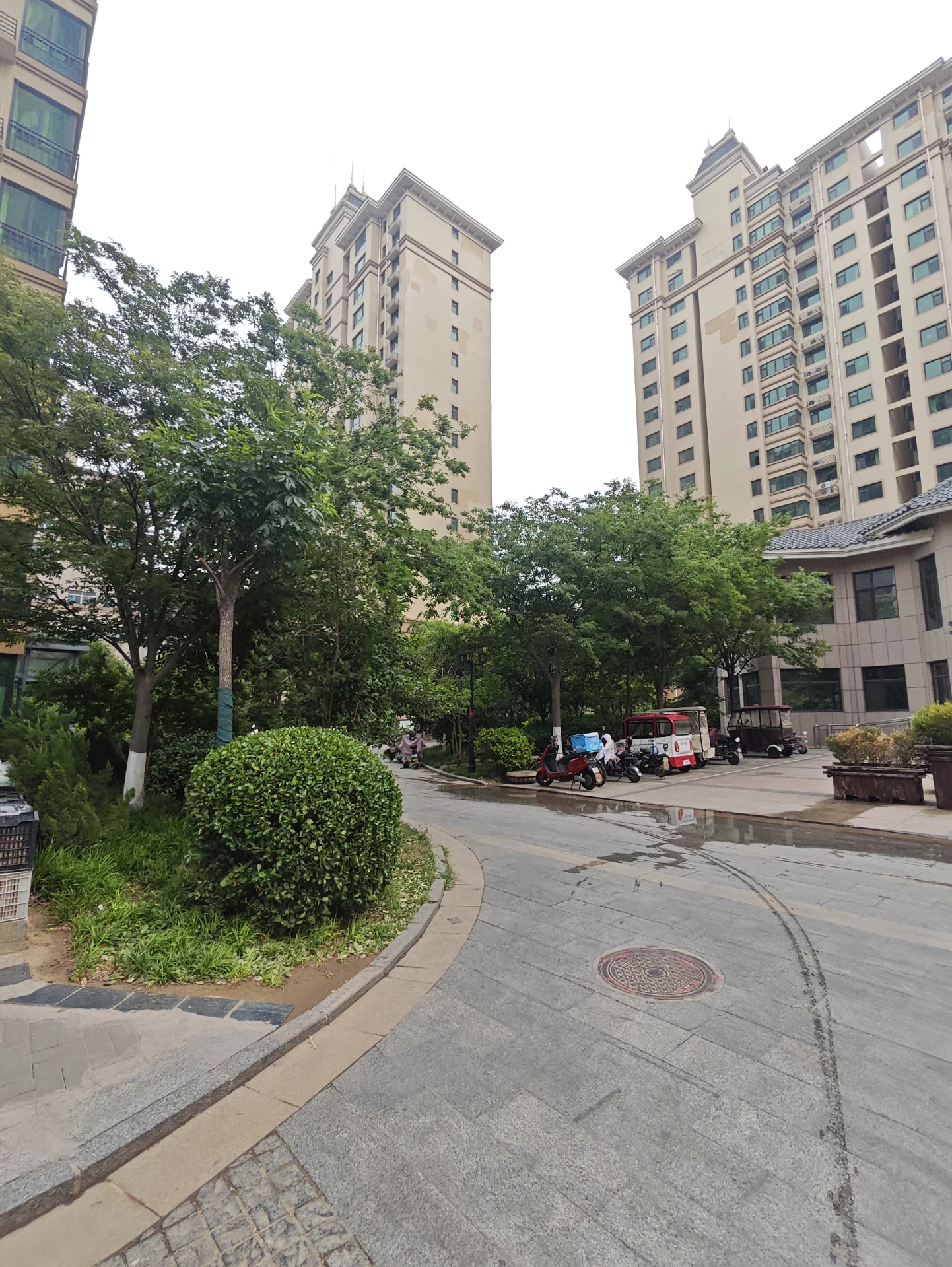 城市街道两侧高耸的建筑物，静谧氛围，车水马龙，自行车停放一旁，现代或当代建筑风格凸显城市感。关键字:城市街道 高耸建筑物 静谧氛围 车水马龙 自行车 现代建筑 当代建筑