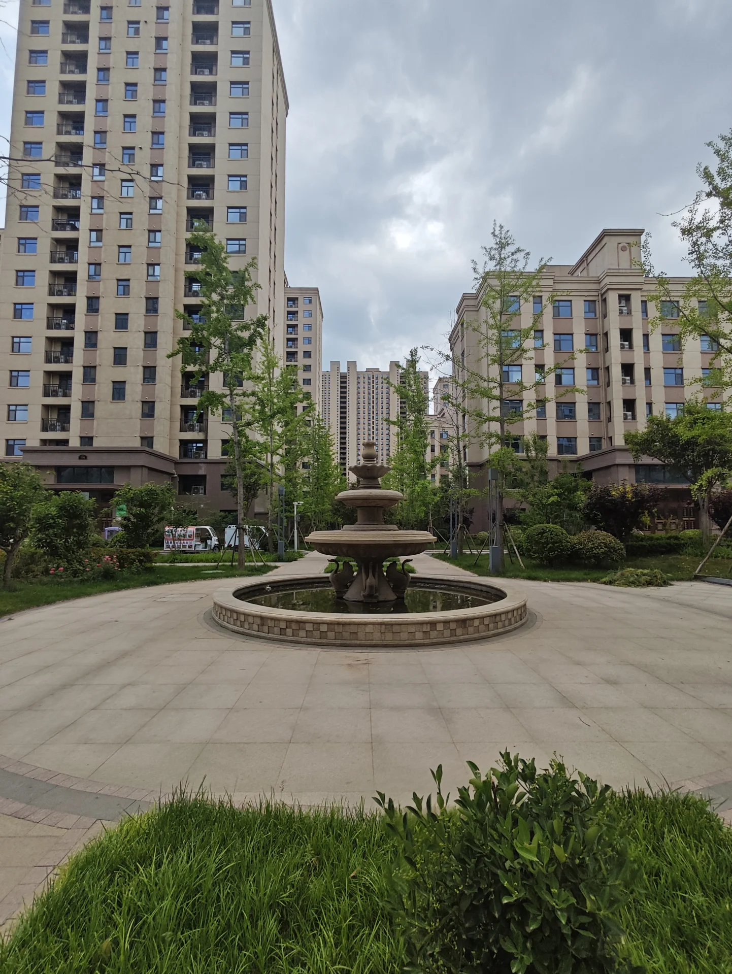 城市公园中央有一座大喷泉，被高楼环绕，营造出 urbanscapes 风格。宁静的氛围，无行人可见。建筑风格现代，增添当代气息。关键字:城市公园 大喷泉 高楼 urbanscapes 风格 宁静氛围 现代建筑