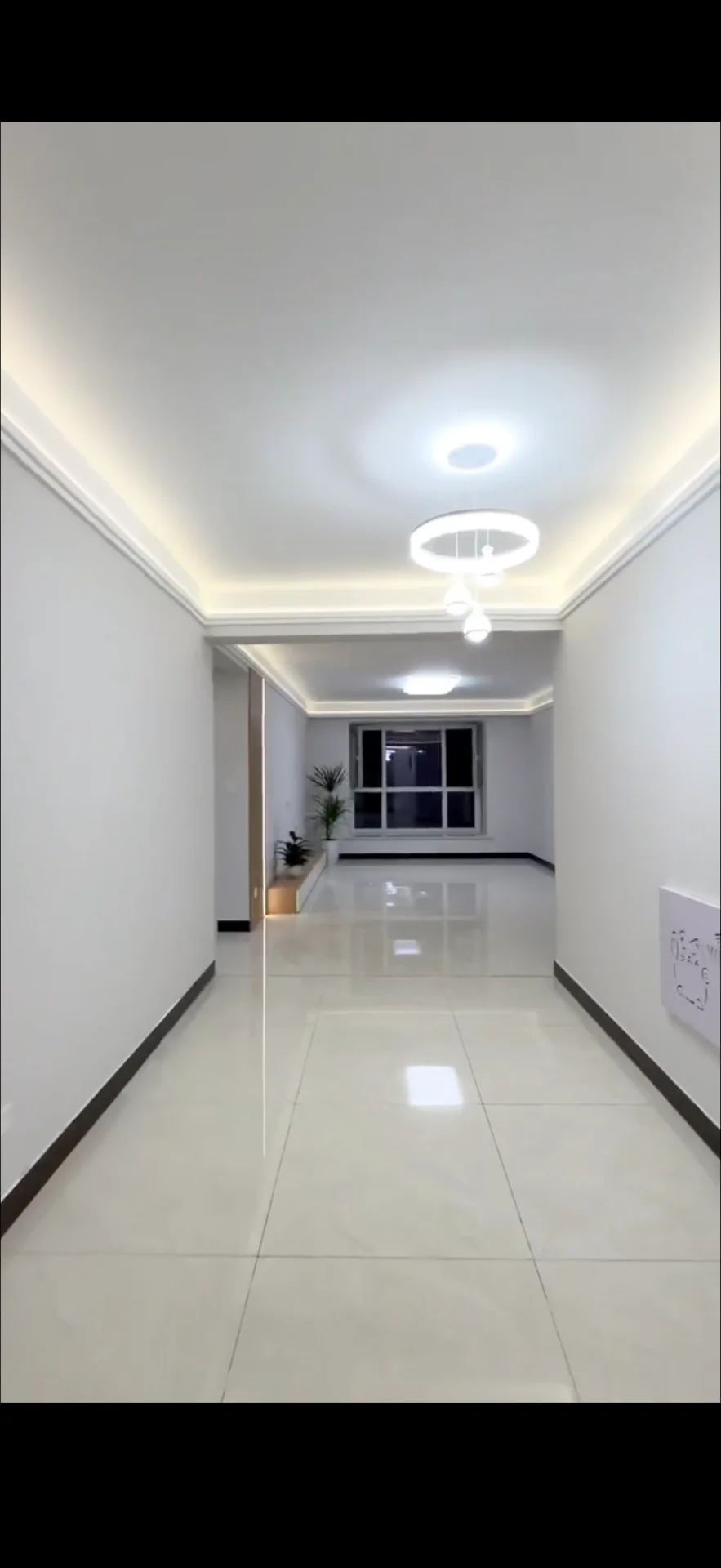 走廊空间，墙面和地面采用浅色大理石纹瓷砖铺设，天花板设计有嵌入式灯带和吊灯，采光均匀明亮，整体呈现现代简约风格。