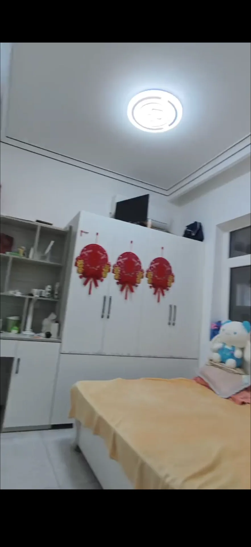 卧室空间，墙面和家具以白色为主色调，配有大型衣柜和床铺。房间内光线充足，整体装修风格简洁明亮，氛围整洁舒适。