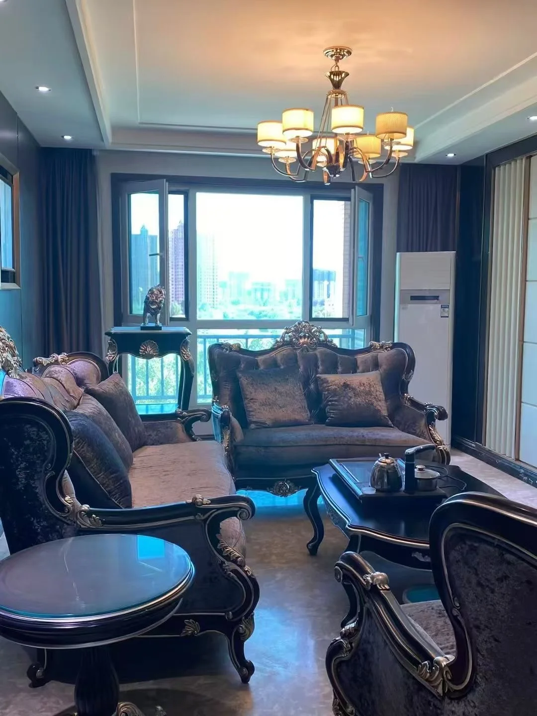 客厅场景，家具采用深色木质框架搭配华丽的软包设计，配有大型水晶吊灯和落地窗。采光良好，整体呈现古典奢华风格，氛围庄重典雅。