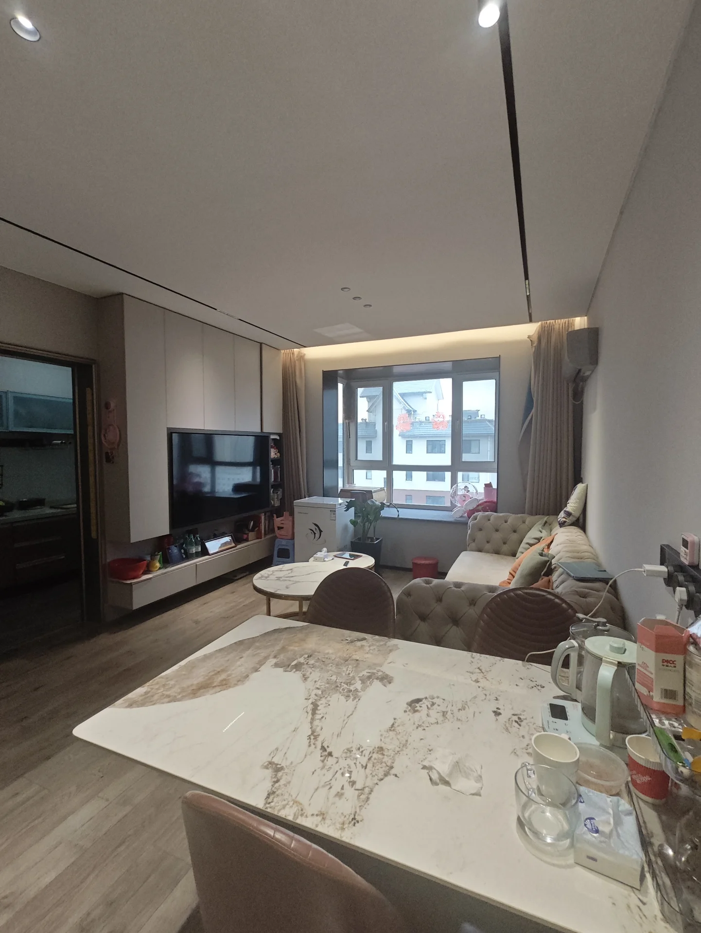 开放式厨房与餐厅区域，采用浅色木纹地板和白色大理石台面设计，配有现代简约风格的家具。空间采光良好，整体环境整洁舒适。