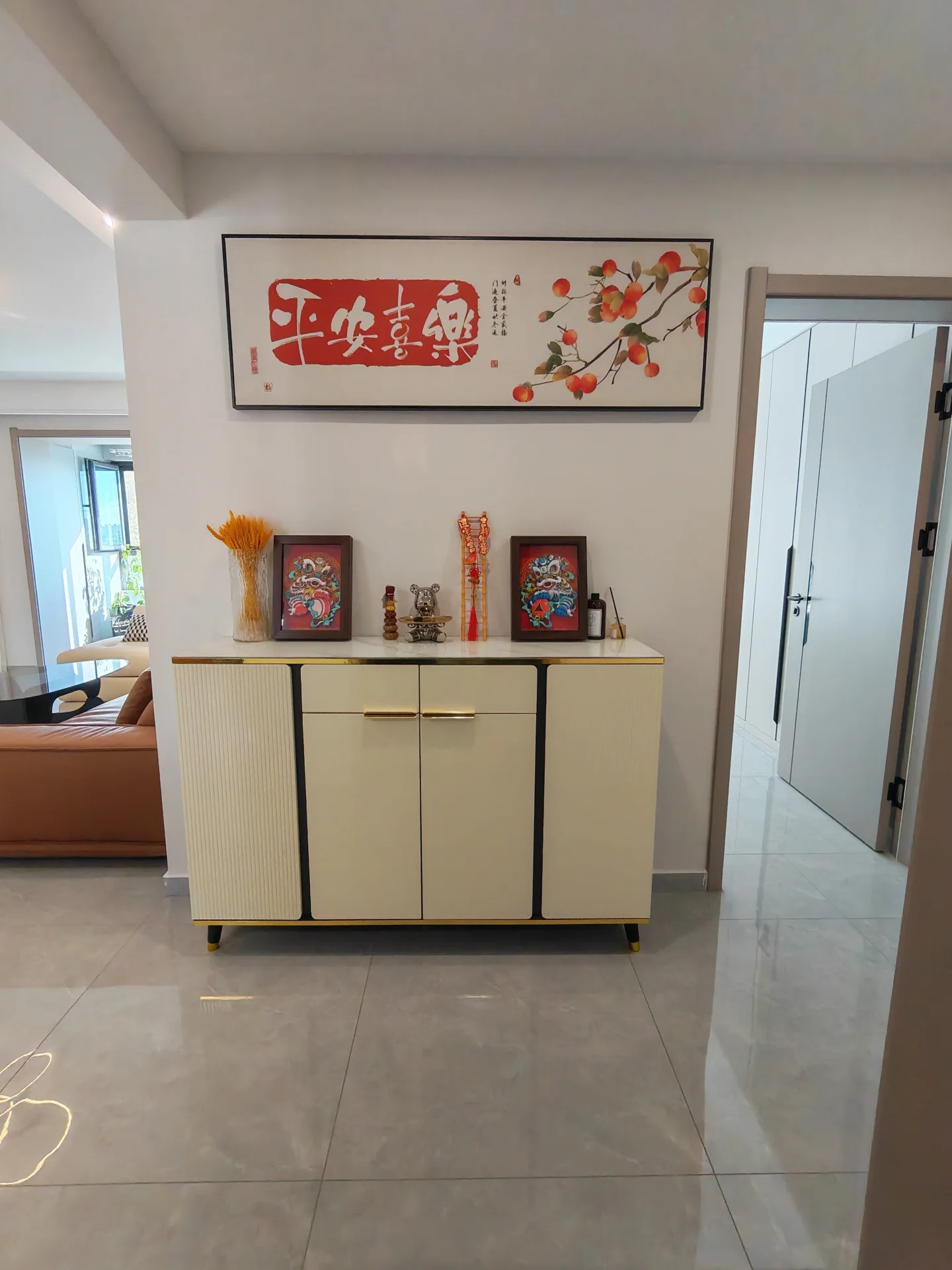 客厅场景，地面铺设大尺寸浅色瓷砖，背景墙上悬挂有大型红色花卉装饰画。家具布局简洁，整体环境光线明亮，呈现出现代简约的家居风格。