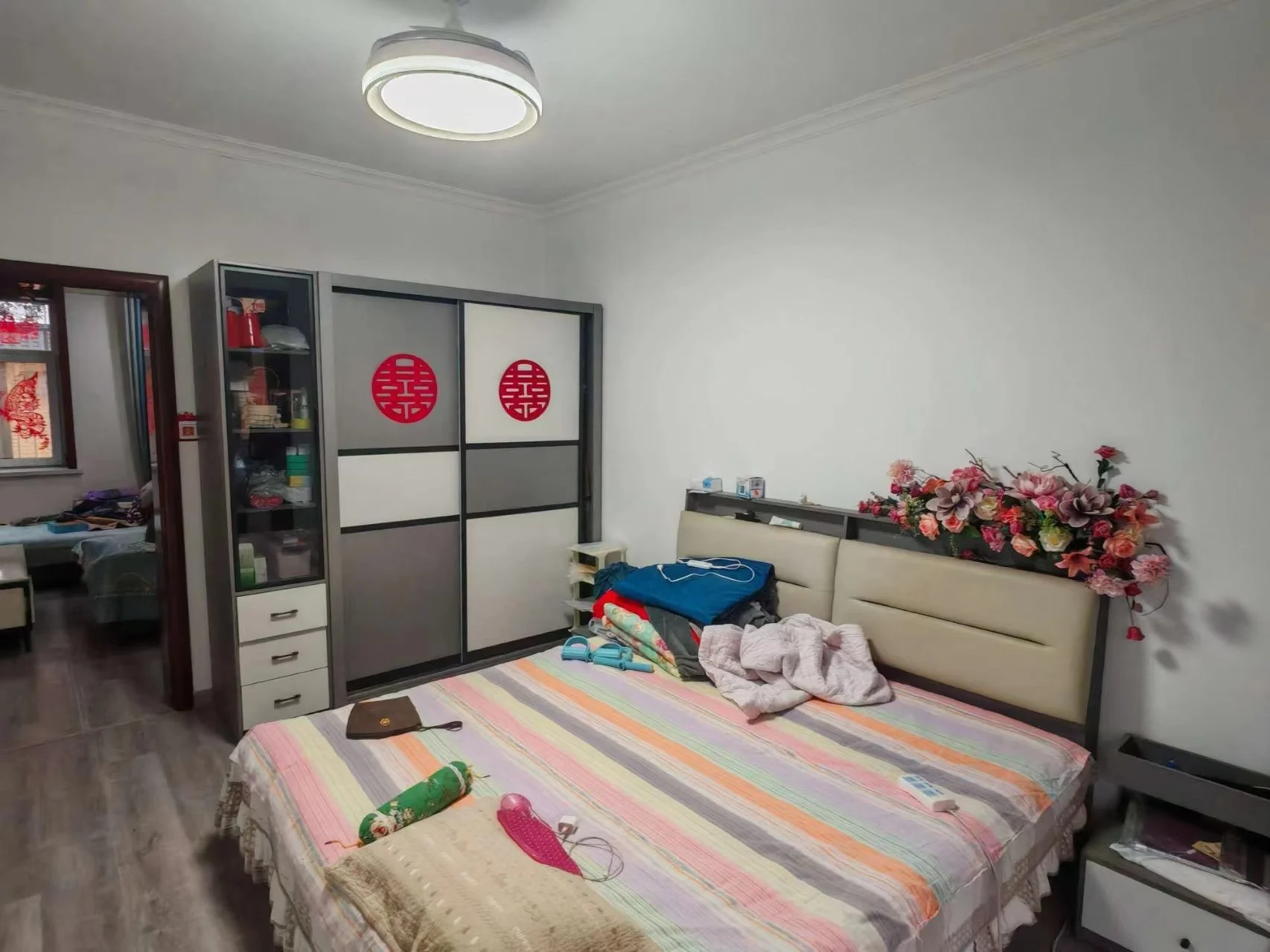 卧室空间，配备大型衣柜和双人床，床铺采用彩色条纹床单装饰。房间整体装修风格简洁，采光适中，环境整洁。