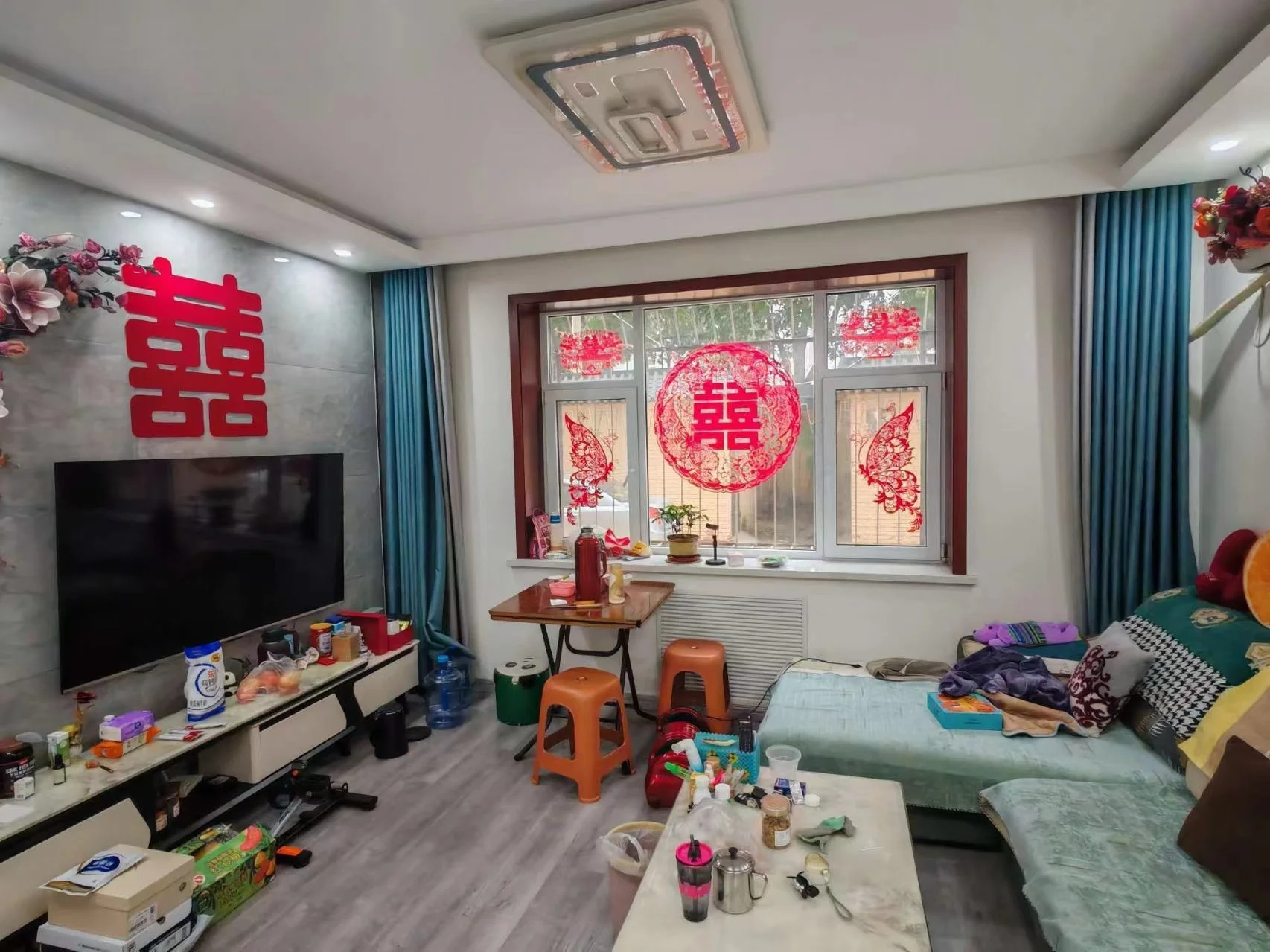 卧室空间，地面铺设浅色木纹地板，配有双人床和电视墙。房间内陈设较为基础，采光适中，整体呈现出实用型的居住氛围。
