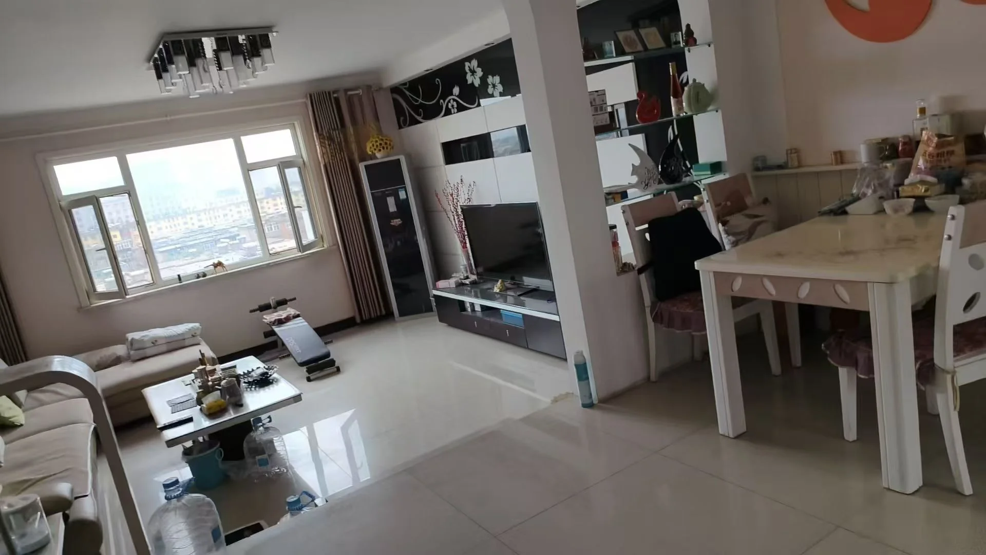 这是一个开放式居住空间，客厅区域配有米色沙发和茶几，采光良好，整体装修风格偏向现代简约。用餐区设有餐桌和椅子，空间布局合理。