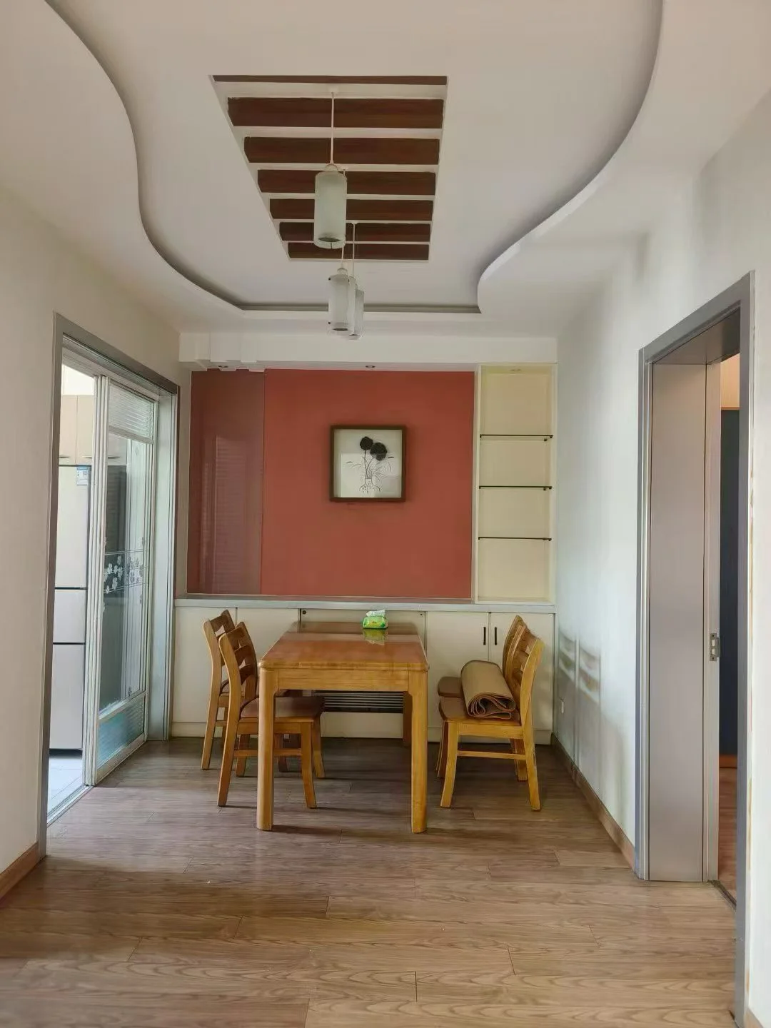 这是一个开放式餐厅空间，墙面采用暖色调设计，配有一张木质餐桌和几把配套的椅子。天花板设计有层次感，整体采光良好，呈现出温馨舒适的居家氛围。