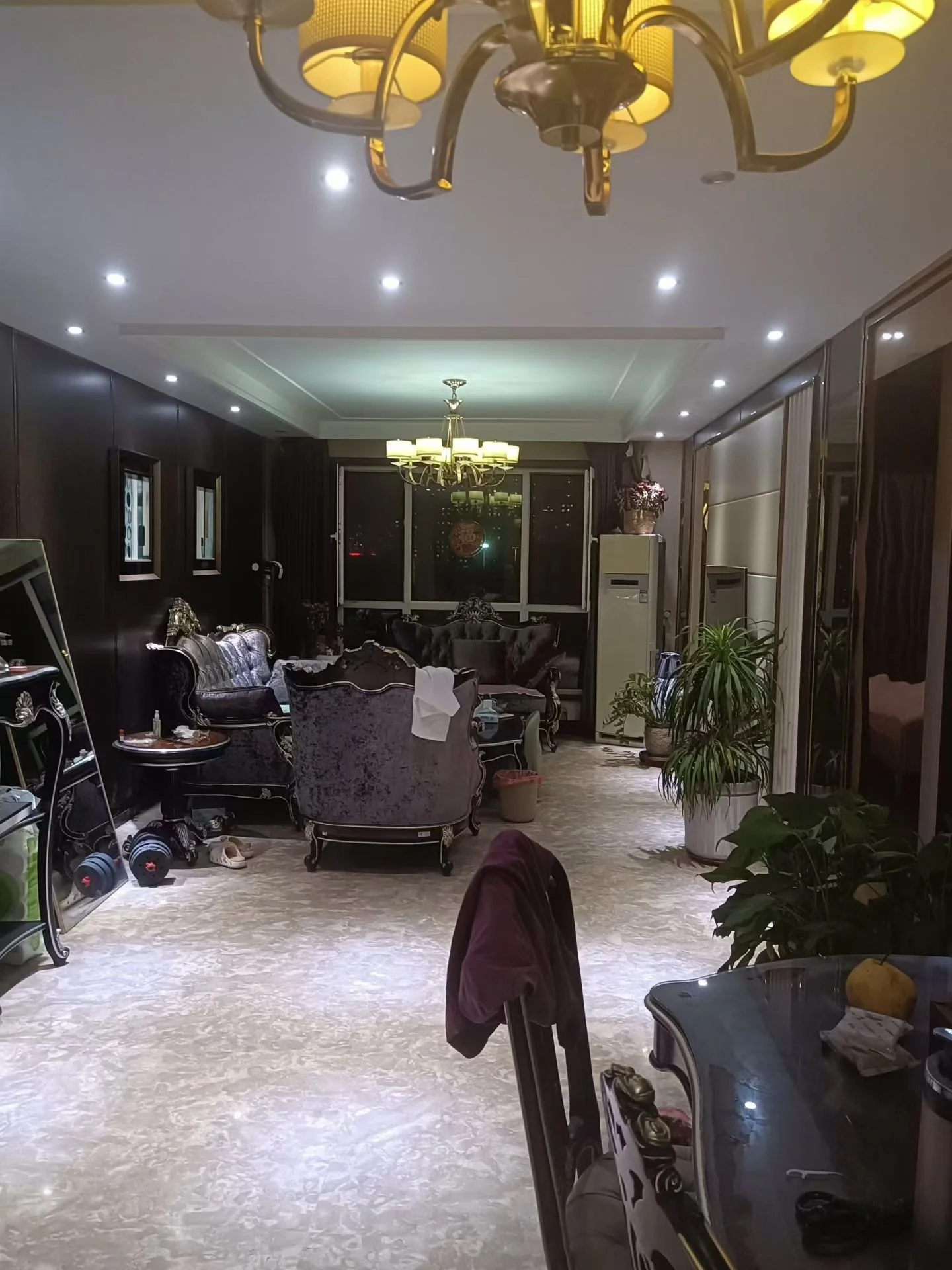 这是一个宽敞的室内空间，家具布置偏向复古或古典风格，包括深色调的沙发和座椅。天花板上悬挂着大型吊灯，整体采光适中，环境显得较为正式和大气。