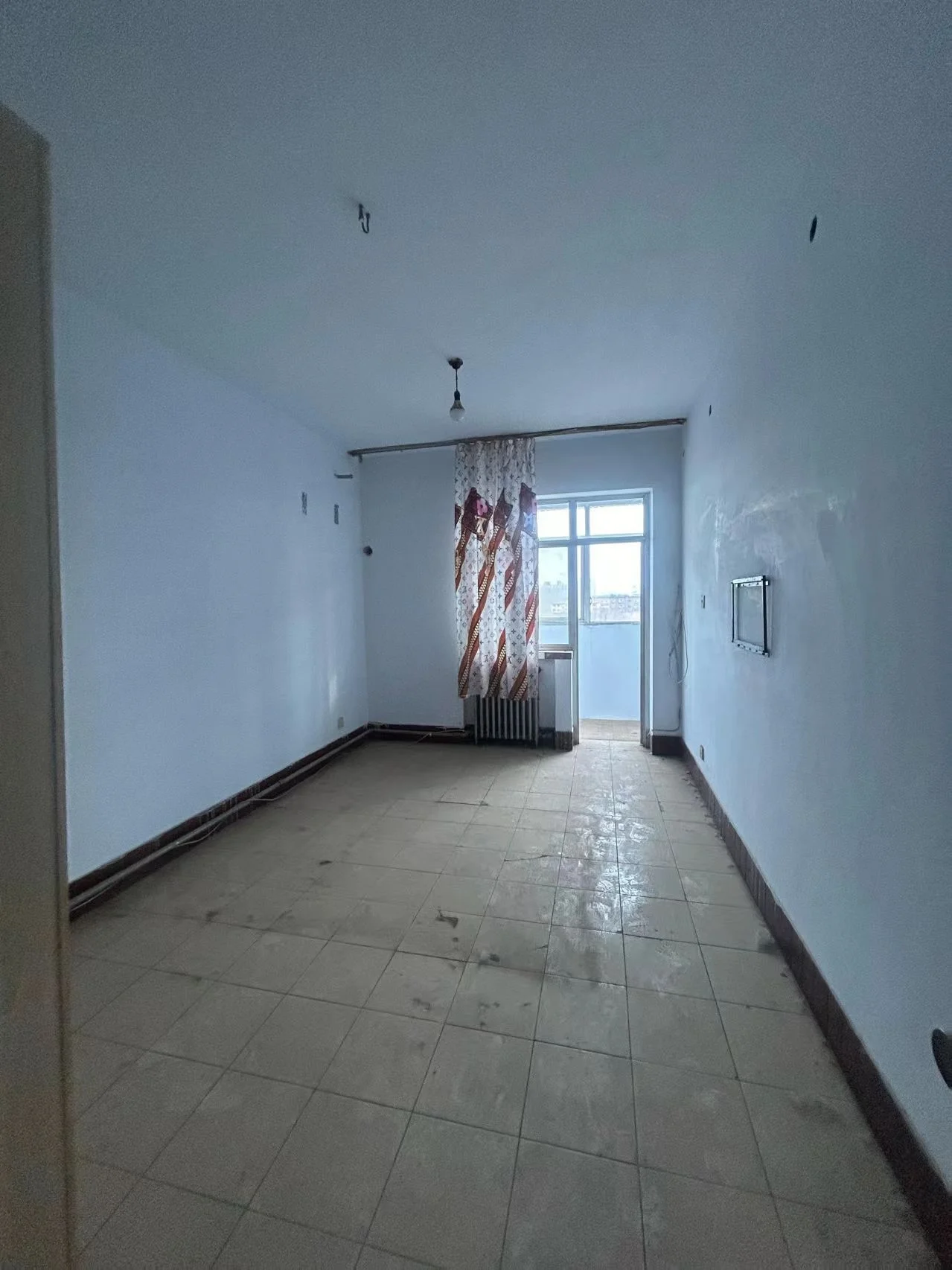 空旷的室内空间，地面铺设浅色瓷砖，墙面为白色，整体装修基础，采光适中，呈现出待装修或刚完工的简约状态。