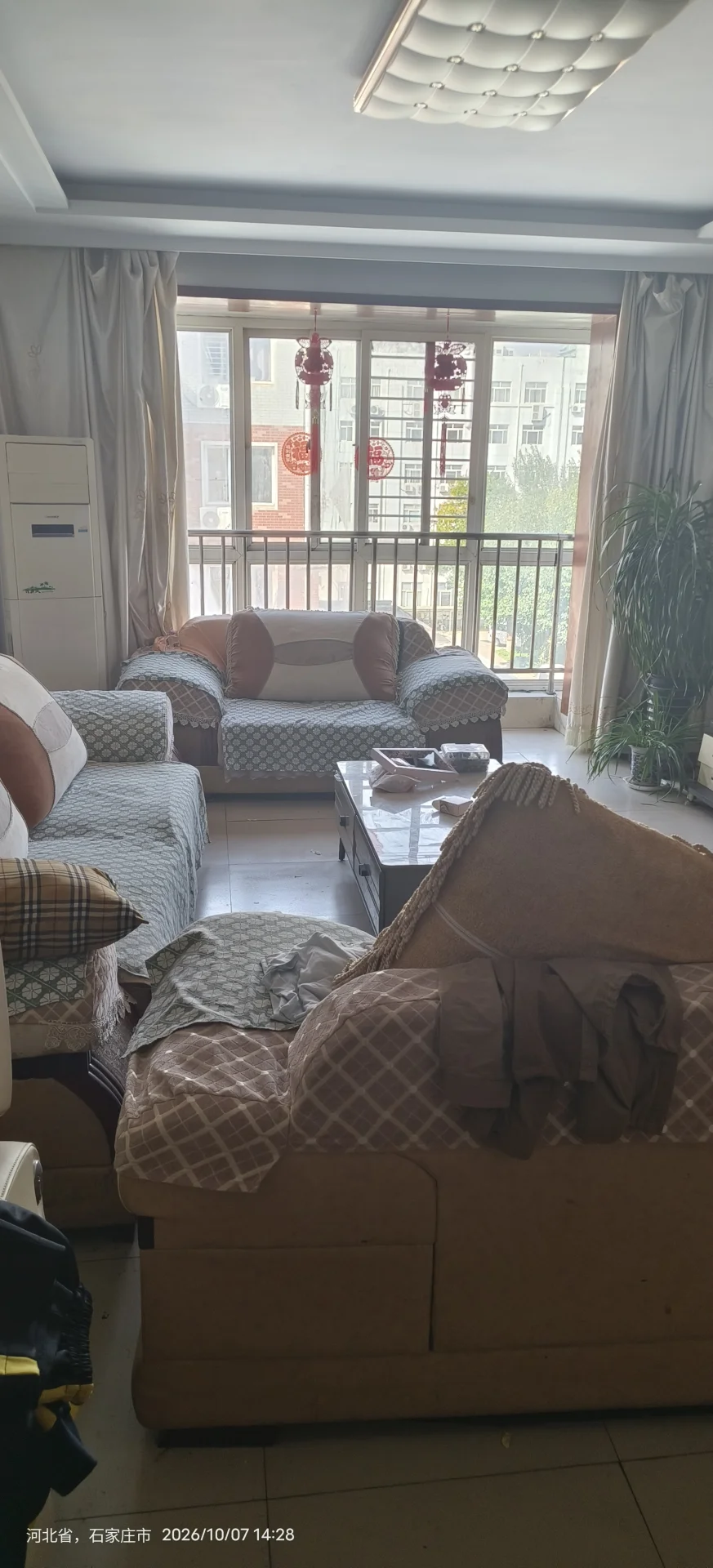 客厅空间，家具为多件布艺沙发，整体装修风格偏基础实用型。采光良好，通过大面积窗户引入自然光，氛围较为日常。