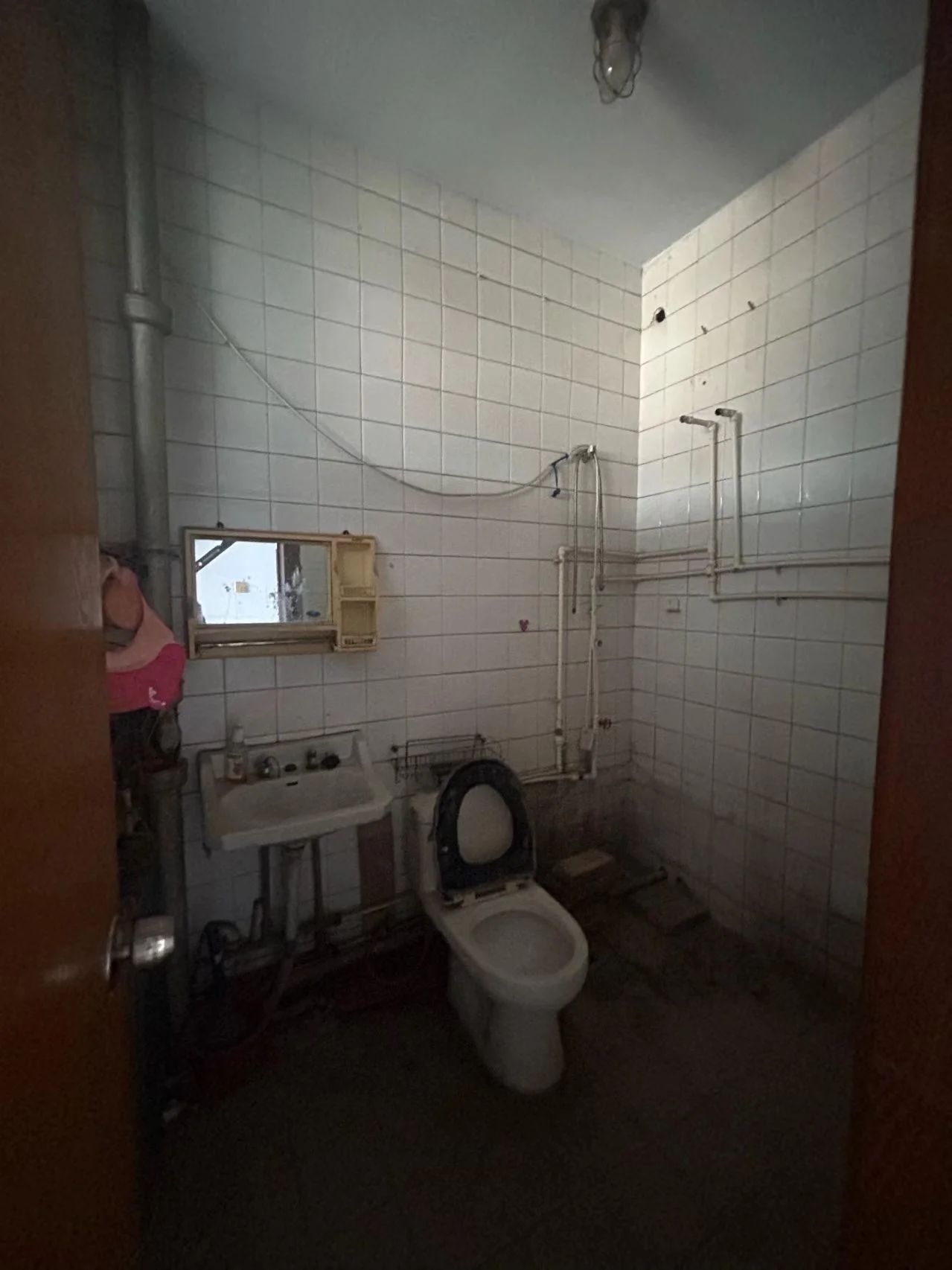 卫生间空间，墙面铺设白色瓷砖，配有白色洗手台和马桶。整体环境基础，光线适中。