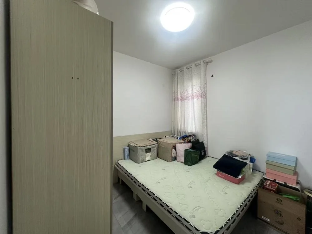 卧室空间，墙面为白色，配有大型衣柜和一张床。房间光线充足，整体装修风格简洁实用，处于基础的居住状态。