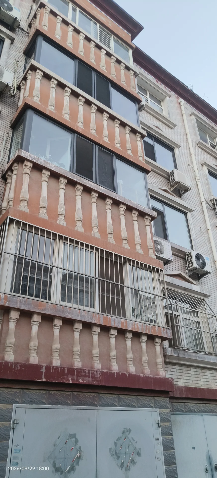 一栋多层住宅建筑，外立面呈现米白色和红棕色调，具有明显的古典或传统风格装饰元素。建筑周围环境较为简洁，整体给人一种成熟的居住氛围。