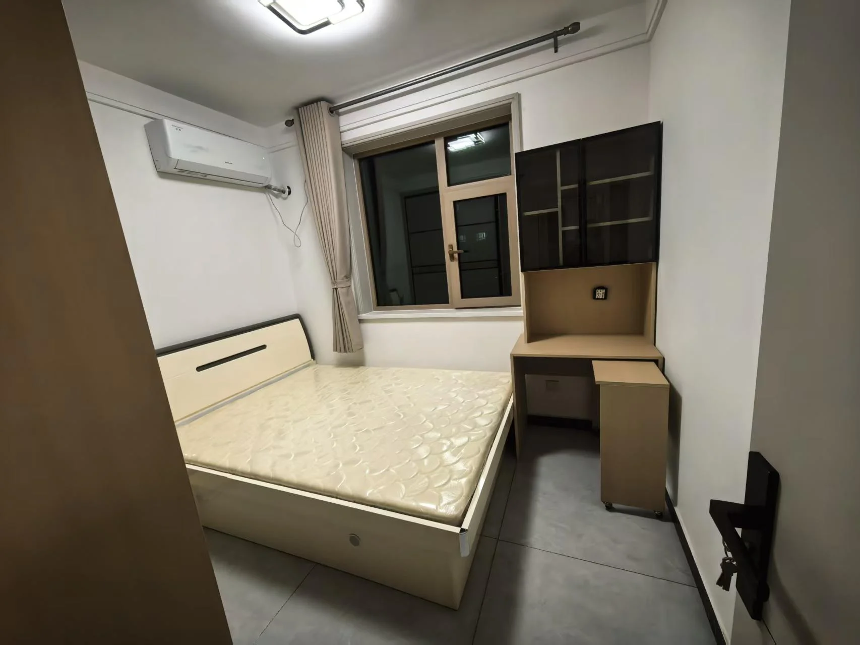 卧室空间，采用浅色调装修，配有大型双人床和书桌衣柜组合。房间采光良好，整体风格简洁实用。