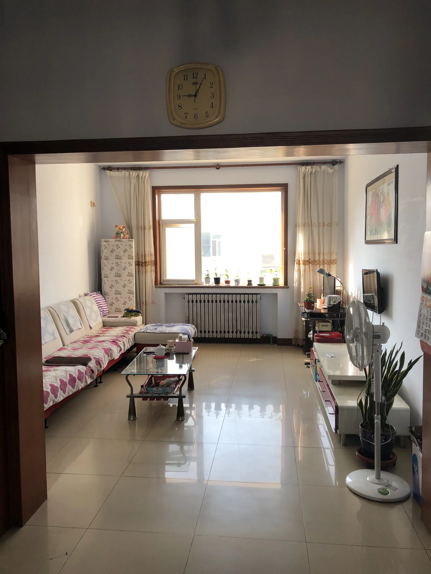 这是一个宽敞的室内空间，地面铺设浅色瓷砖，配有几张床和一张茶几。房间内光线充足，整体装修风格偏基础实用型。
