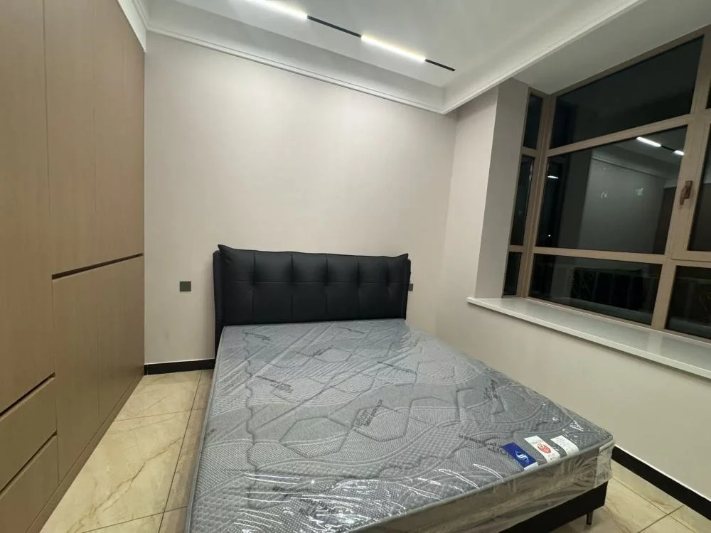 卧室空间，配有深色软包床和大型衣柜，地面铺设浅色瓷砖。房间采光良好，整体呈现现代简约风格，环境整洁。