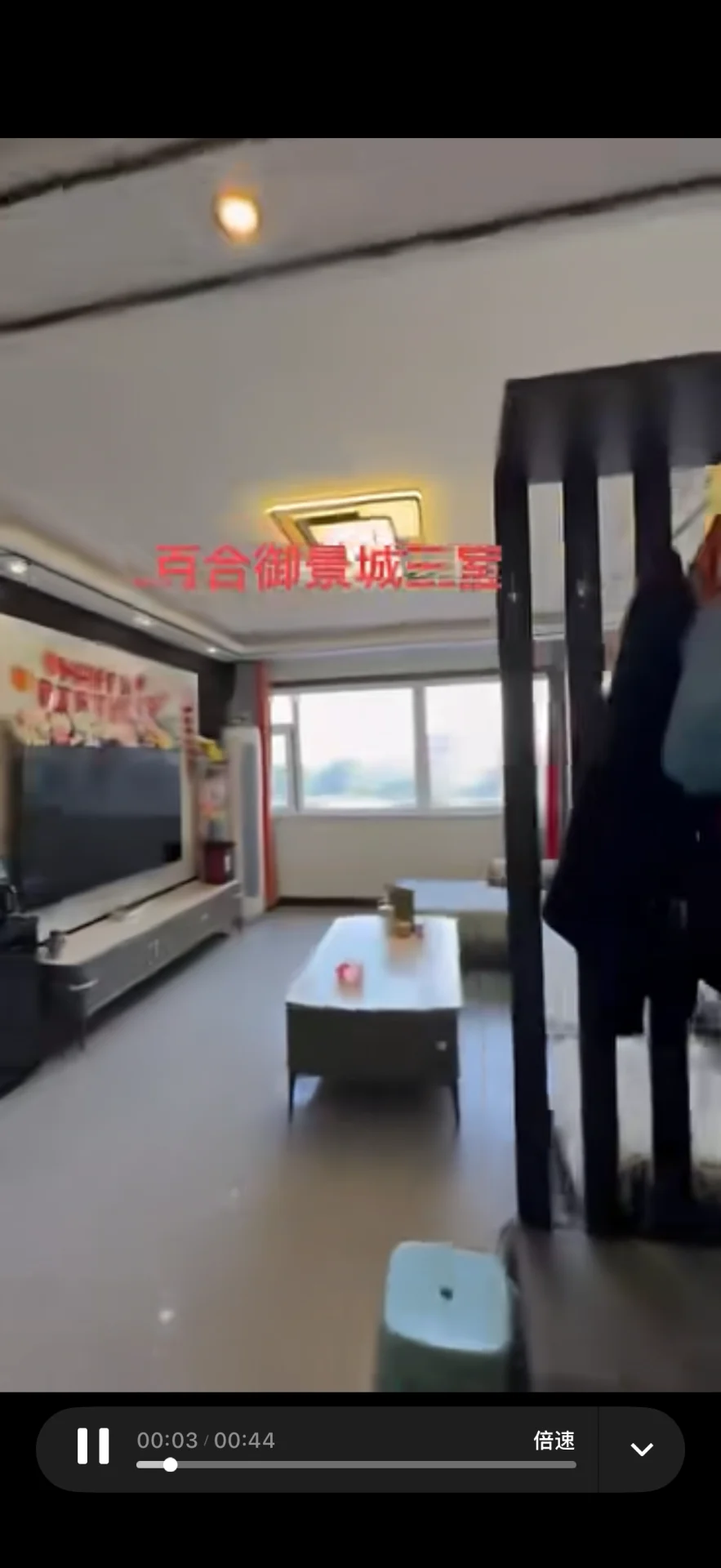 客厅空间，地面为浅色瓷砖，配有大型电视和简约茶几。房间采光适中，整体装修风格偏基础实用型。