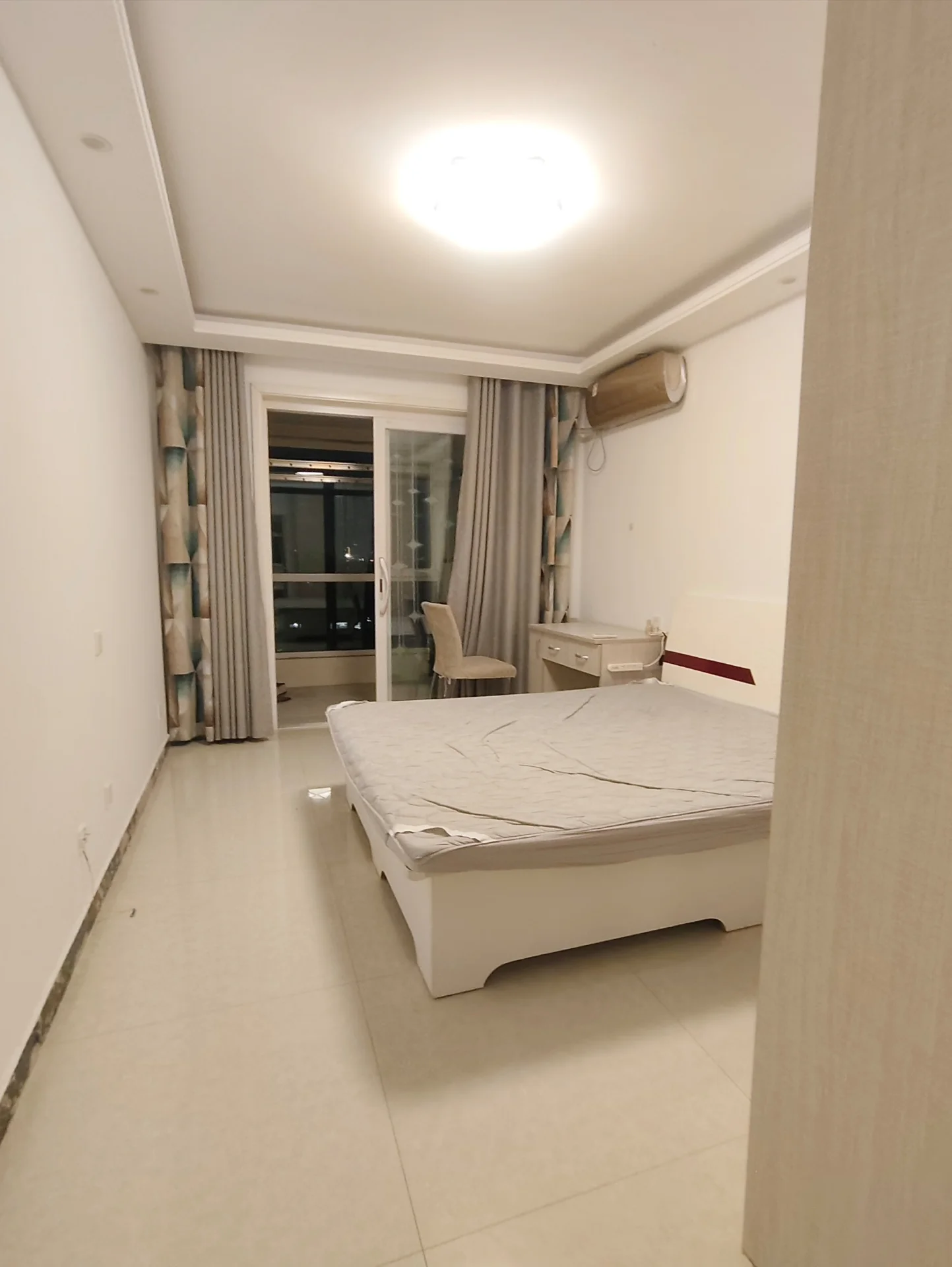 卧室空间，地面铺设浅色瓷砖，配有大型床铺和衣柜。房间采光良好，整体装修风格简洁实用，氛围整洁明亮。