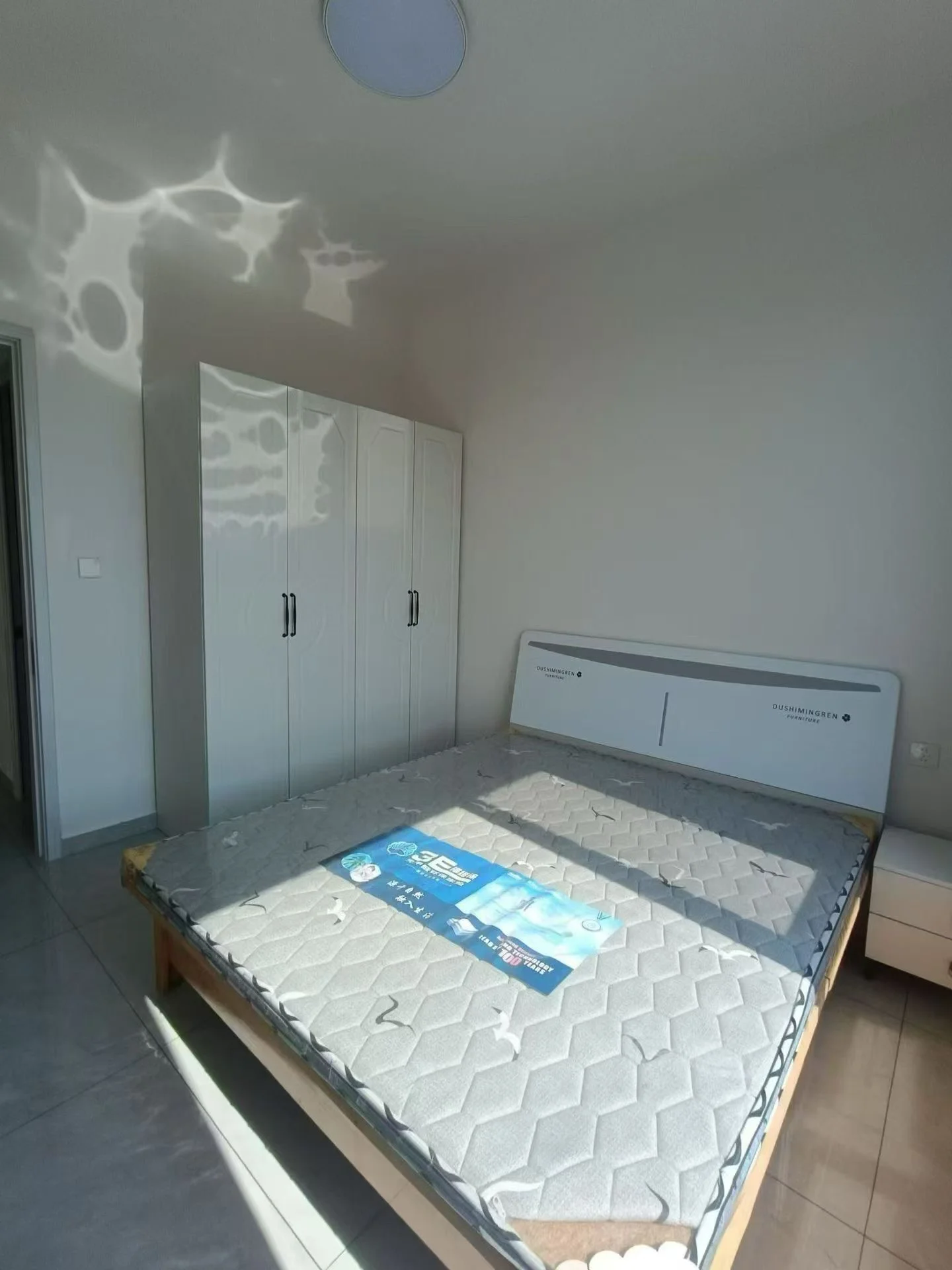 卧室空间，配备白色衣柜和大型床铺。房间光线充足，整体装修风格简洁明快，属于基础居住环境。