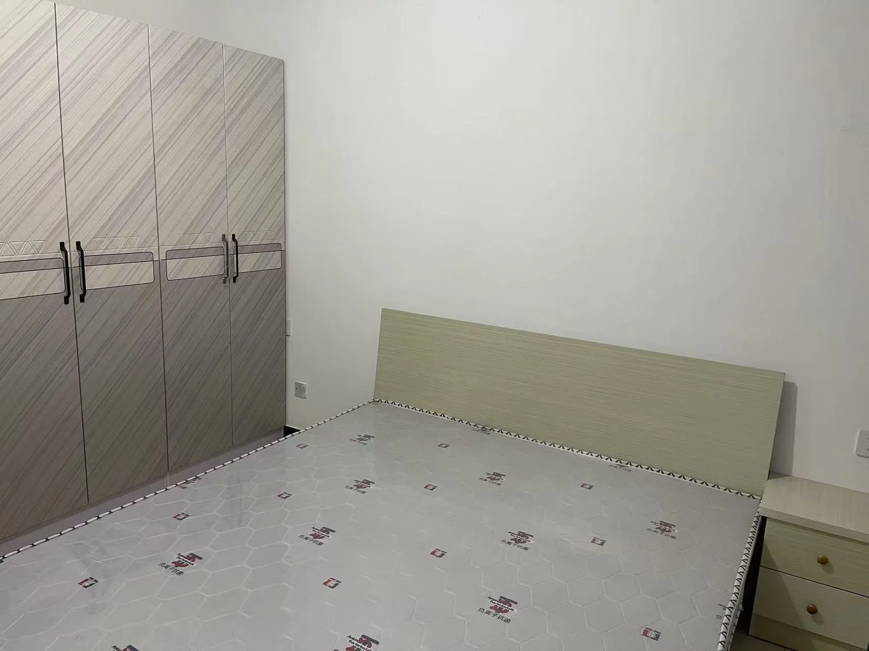 卧室空间，配备大型衣柜和床铺。墙面为简洁的白色，地面铺设带有几何图案的瓷砖，整体装修风格偏向现代简约，光线均匀明亮。