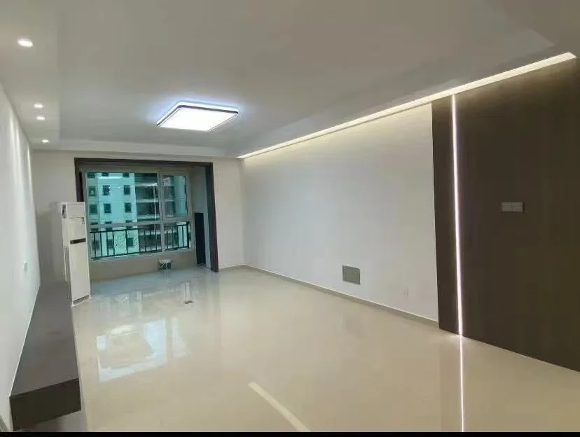 这是一个空旷的室内空间，地面铺设浅色光亮瓷砖，墙面简洁，天花板嵌入了方形照明灯具。整体装修风格偏向现代简约，采光良好，处于待装修或刚完工的状态。