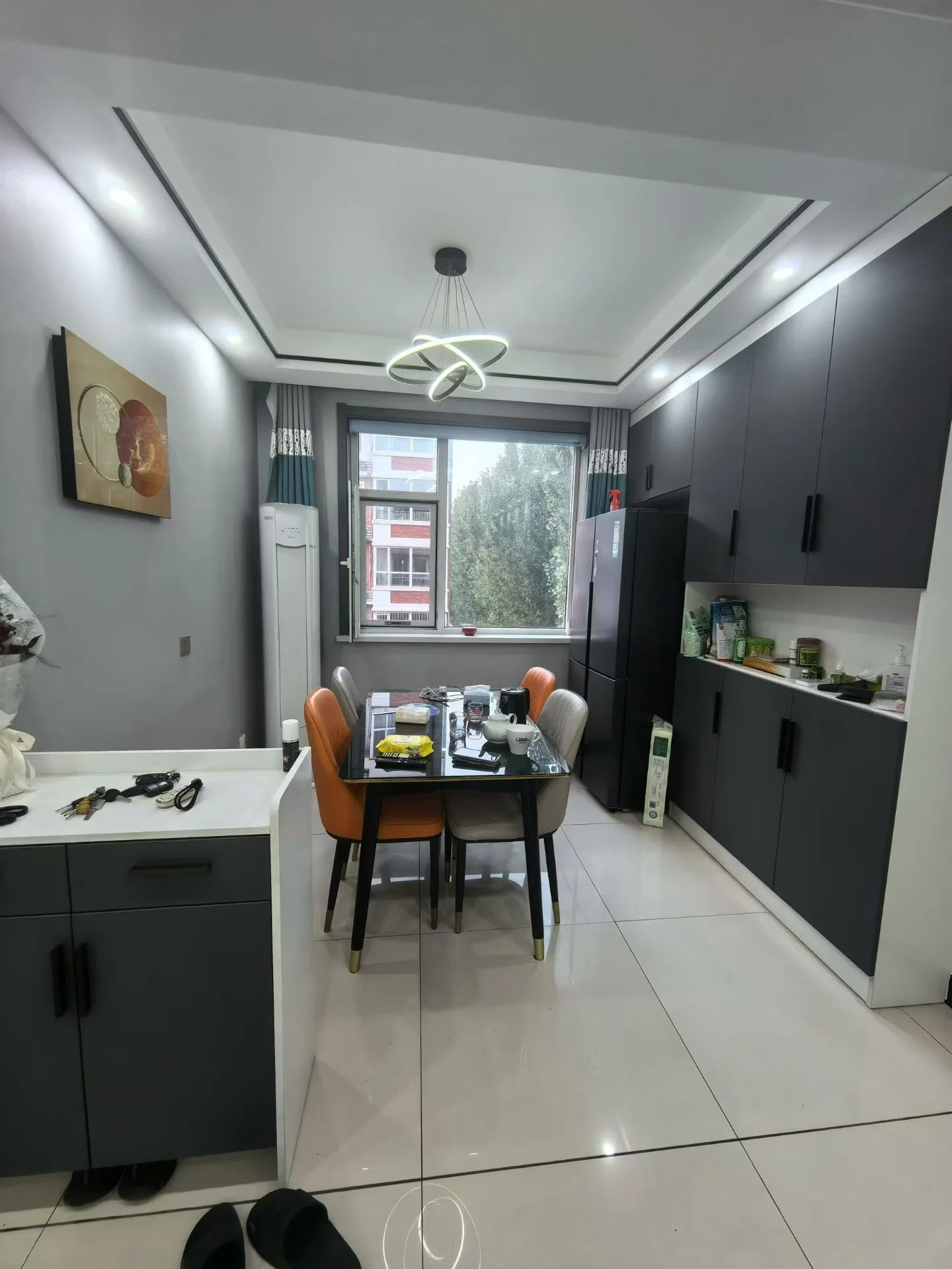 开放式厨房与餐厅区域，采用深灰色橱柜设计，搭配白色大理石纹地砖。空间布局简洁现代，采光良好，整体装修风格偏向现代简约。