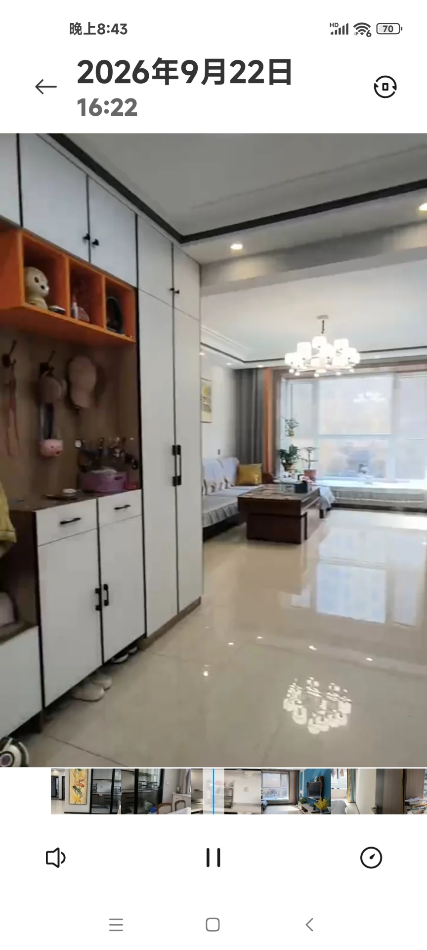 这是一个宽敞的室内空间，主要展示了客厅区域，地面为高光抛光材质，配有大型吊灯和简约风格的沙发区。整体采光良好，装修风格偏向现代简约。