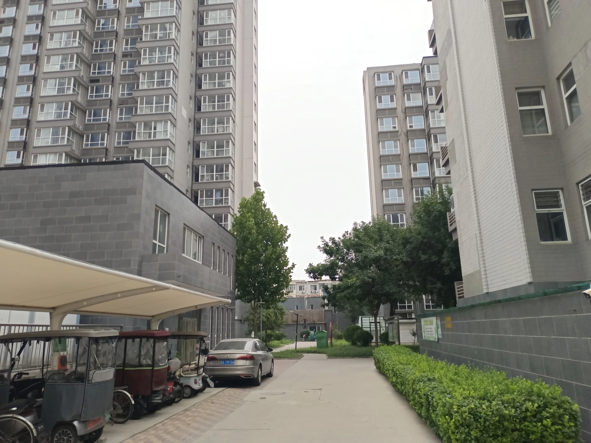 两栋高层住宅建筑对称分布在街道两侧，中间有道路和绿化带穿过。建筑风格现代，外立面简洁，整体环境整洁有序，展现出成熟的城市居住氛围。
