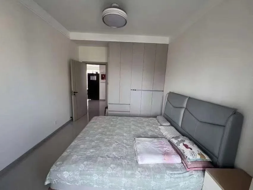 卧室空间，墙面和天花板为白色，配有大型衣柜和一张双人床。房间采光适中，整体呈现简洁的基础装修风格。