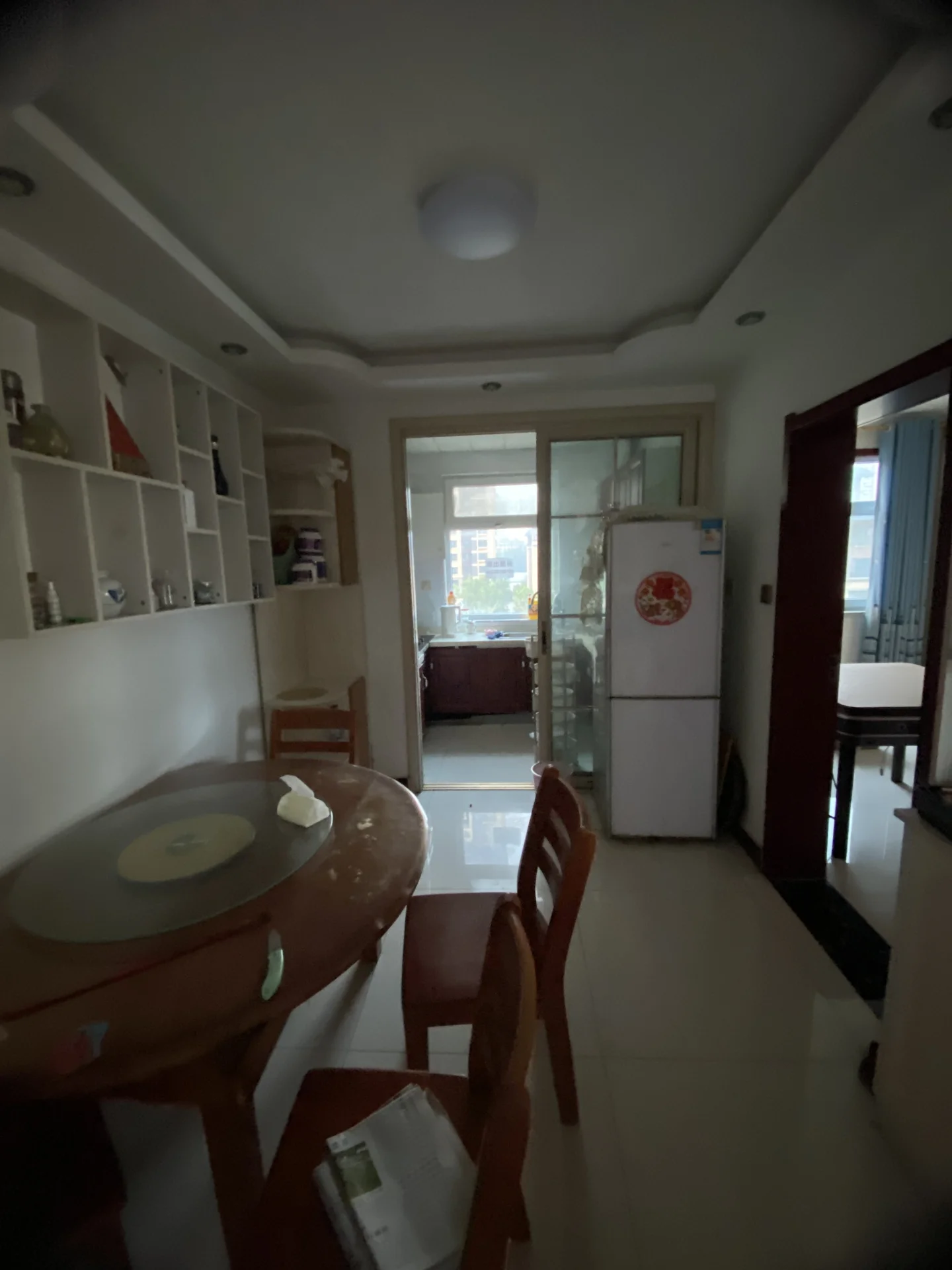 餐厅和部分开放式厨房区域，木质餐桌配有简约椅子，墙面嵌入式储物柜提供收纳空间。室内光线均匀，整体装修风格偏向实用和简洁。