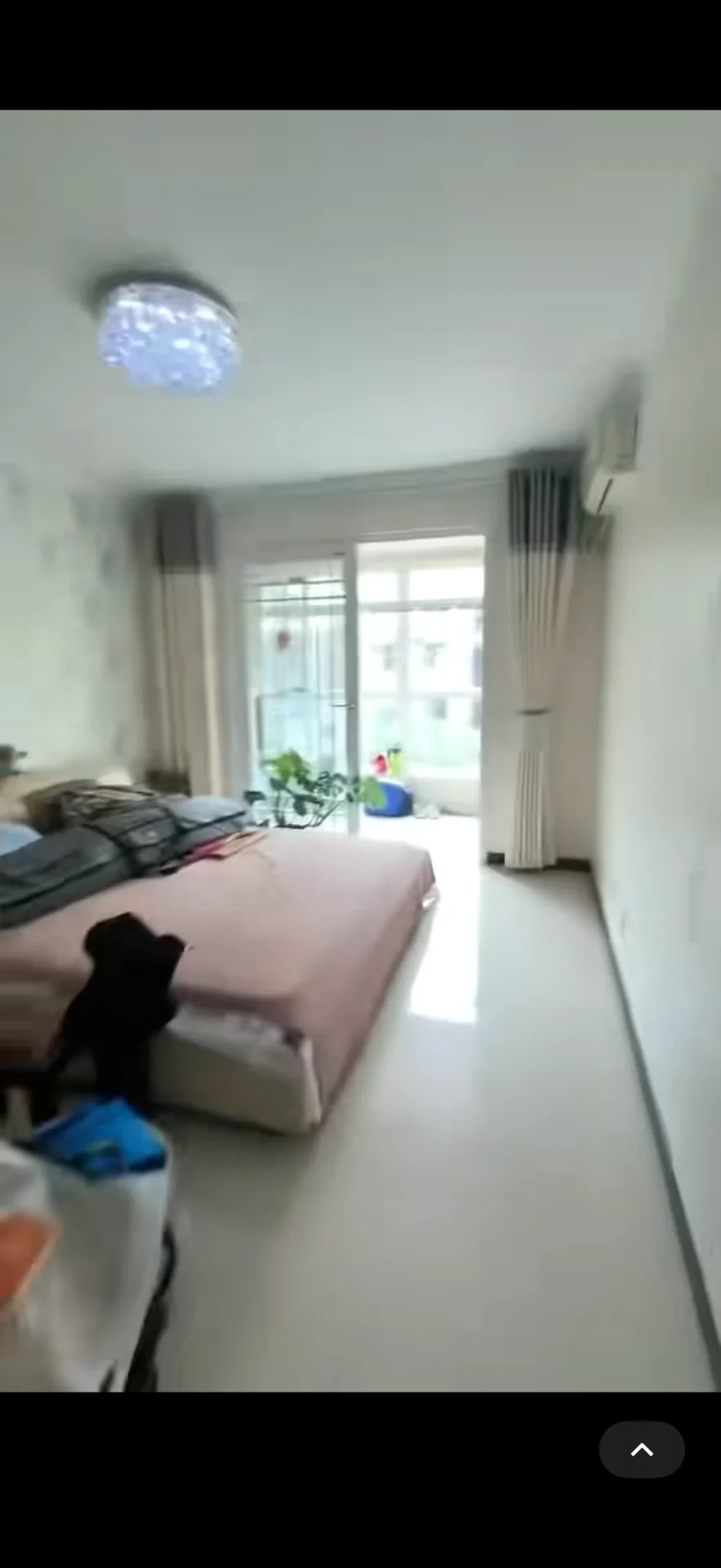 卧室空间，墙面和天花板为白色调，配有大型床铺和简约的吊灯。采光良好，整体呈现简洁明亮的现代风格。